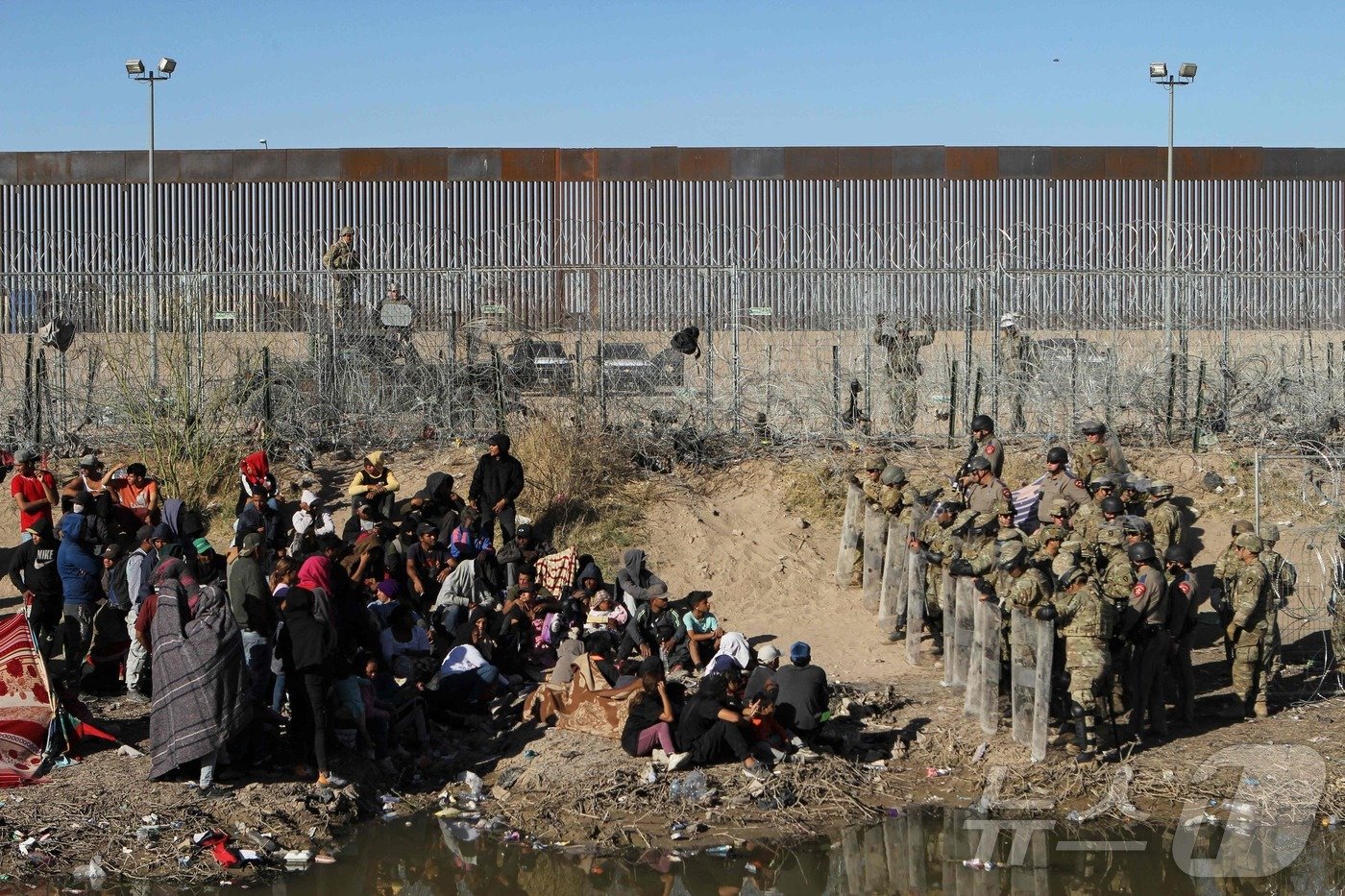 본문 이미지 - 미국 텍사스주 방위군과 고속도로 경찰이 지난 3월 22일(현지시간) 멕시코 시우다드 후아레스 리오그란데 강둑에서 베네수엘라 이주민들을 철수시키고 있다. 2024.03.22. ⓒ AFP=뉴스1 ⓒ News1 김종훈 기자