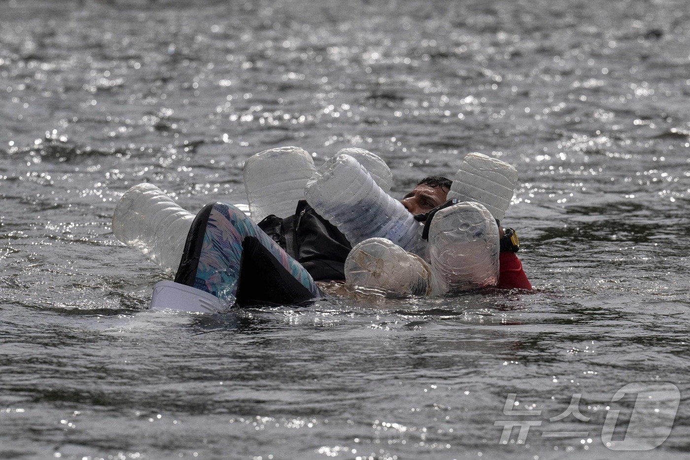 본문 이미지 - 한 베네수엘라 이민자가 지난 2023년 9월 21일(현지시간) 파나마 다리엔주에 있는 첫 국경 검문소가 있는 바호 치키토 인근에서 페트병을 이용해 강을 건너고 있다. 2023.09.21. ⓒ AFP=뉴스1 ⓒ News1 김종훈 기자