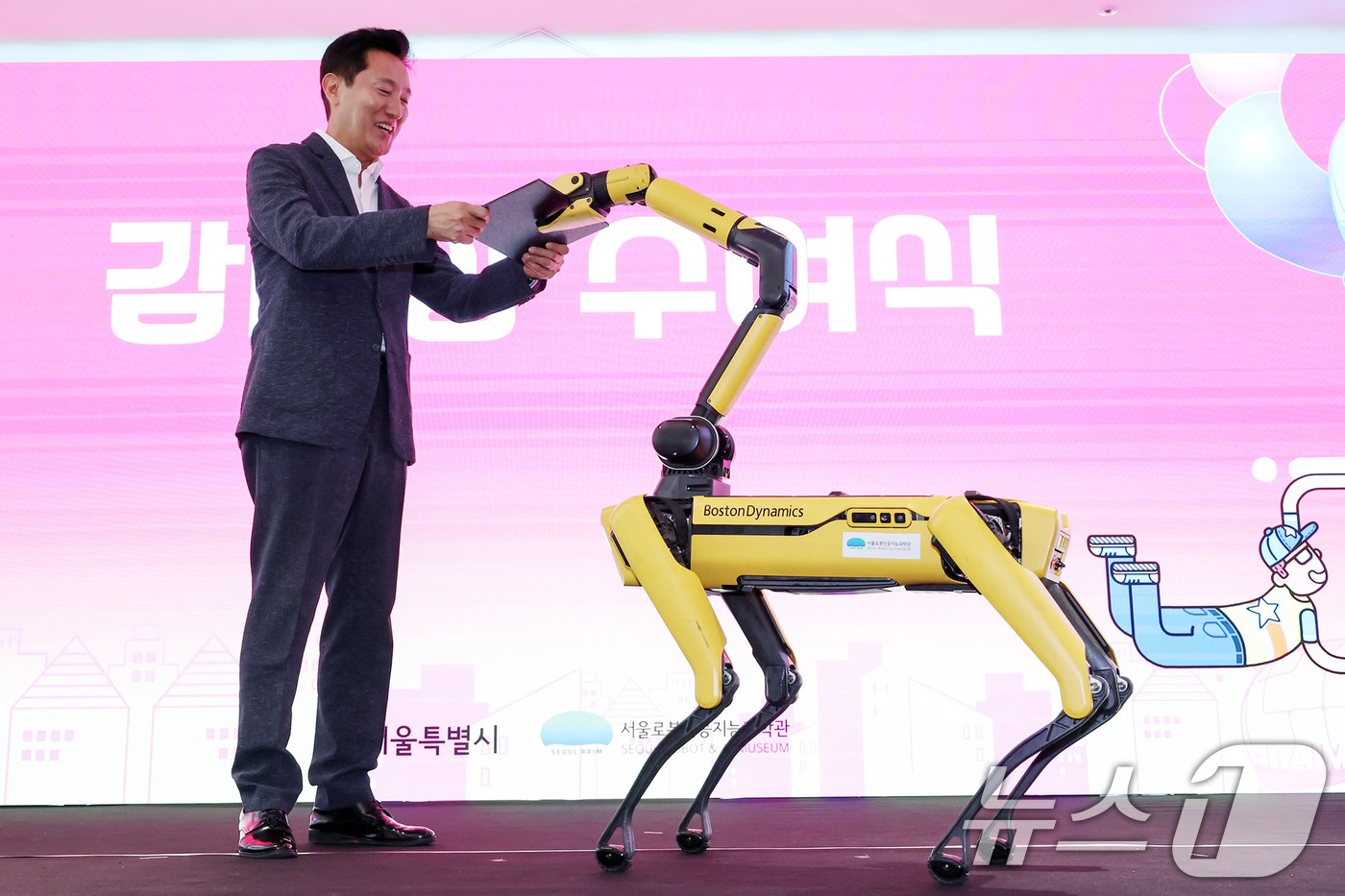 본문 이미지 - 오세훈 서울시장이 20일 서울 도봉구 서울로봇인공지능과학관에서 열린 개관식에 참석해 로봇 개(4족 보행로봇)로부터 시상식 상장을 건네받고 있다. 2024.8.20/뉴스1 ⓒ News1 민경석 기자