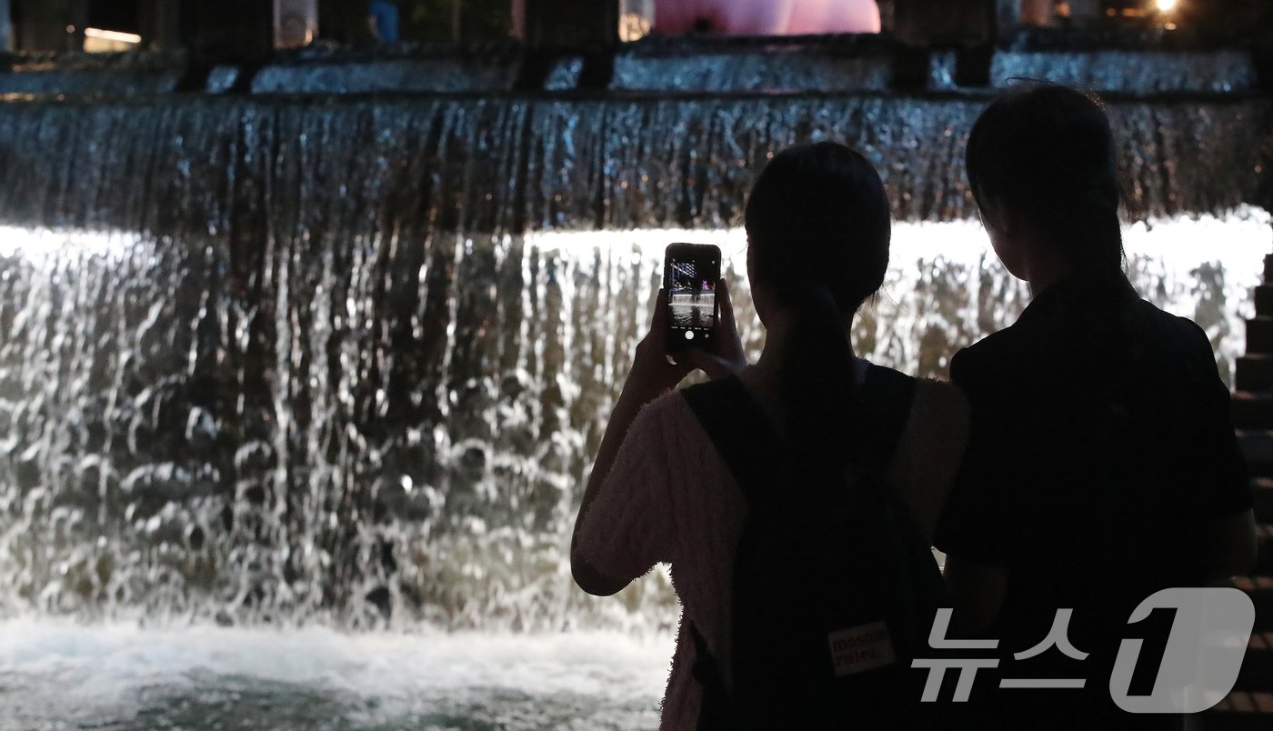 본문 이미지 - 열대야가 이어지는 21일 서울 청계천을 찾은 시민들이 시원하게 떨어지는 인공폭포를 휴대폰으로 사진 찍고 있다. 2024.8.21/뉴스1 ⓒ News1 박세연 기자