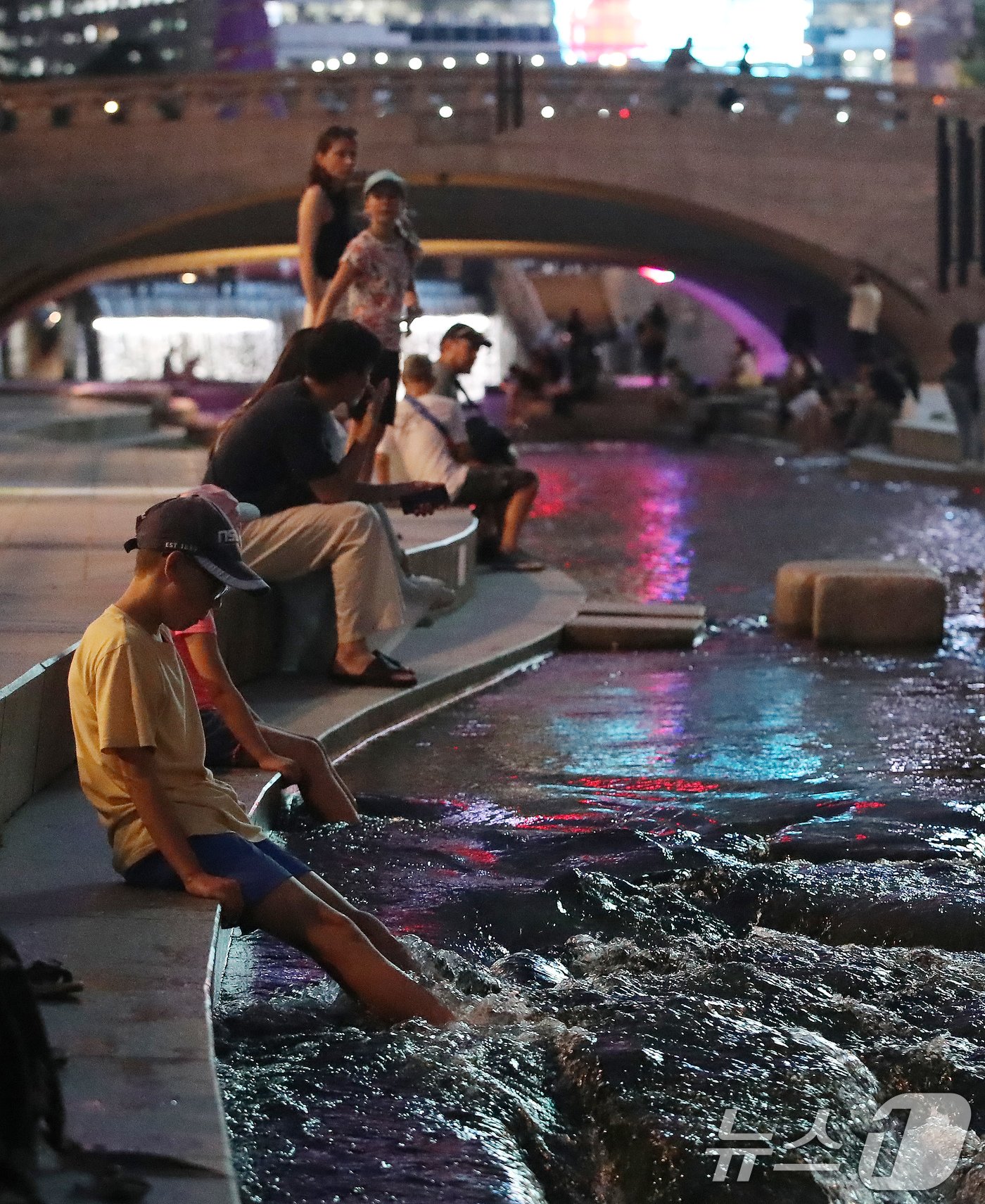 본문 이미지 - 열대야가 이어지는 21일 오후 서울 청계천을 찾은 외국인 관광객들이 청계천에 발을 담그며 더위를 식히고 있다. 2024.8.21/뉴스1 ⓒ News1 박세연 기자