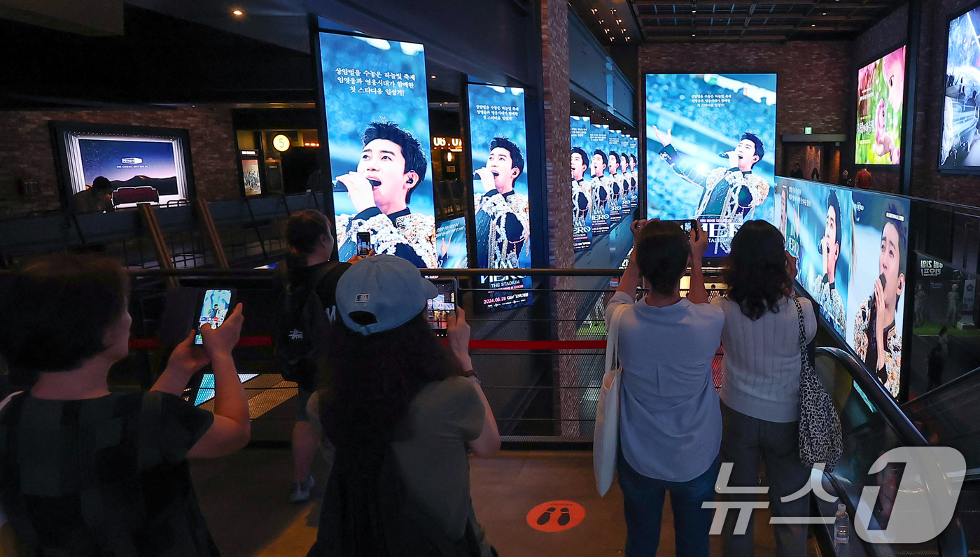 (서울=뉴스1) 김진환 기자 = 22일 오후 서울 CGV 용산아이파크몰을 찾은 시민들이 ‘임영웅│아임 히어로 더 스타디움’ 광고 영상을 스마트폰으로 촬영하고 있다.10만 영웅시대와 …