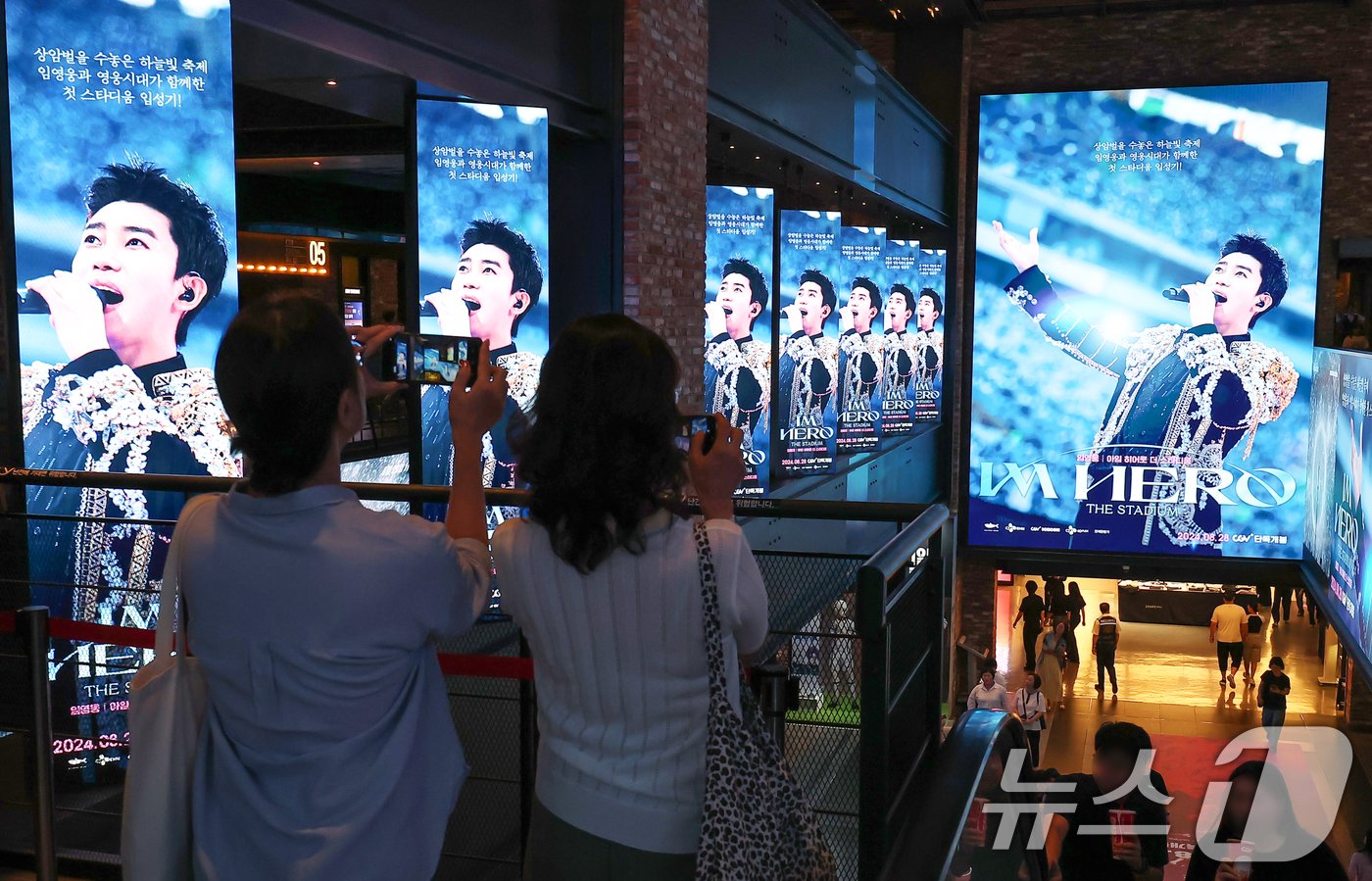 본문 이미지 - 22일 오후 서울 CGV 용산아이파크몰을 찾은 시민들이 ‘임영웅│아임 히어로 더 스타디움’ 광고 영상을 스마트폰으로 촬영하고 있다.  ⓒ News1 김진환 기자