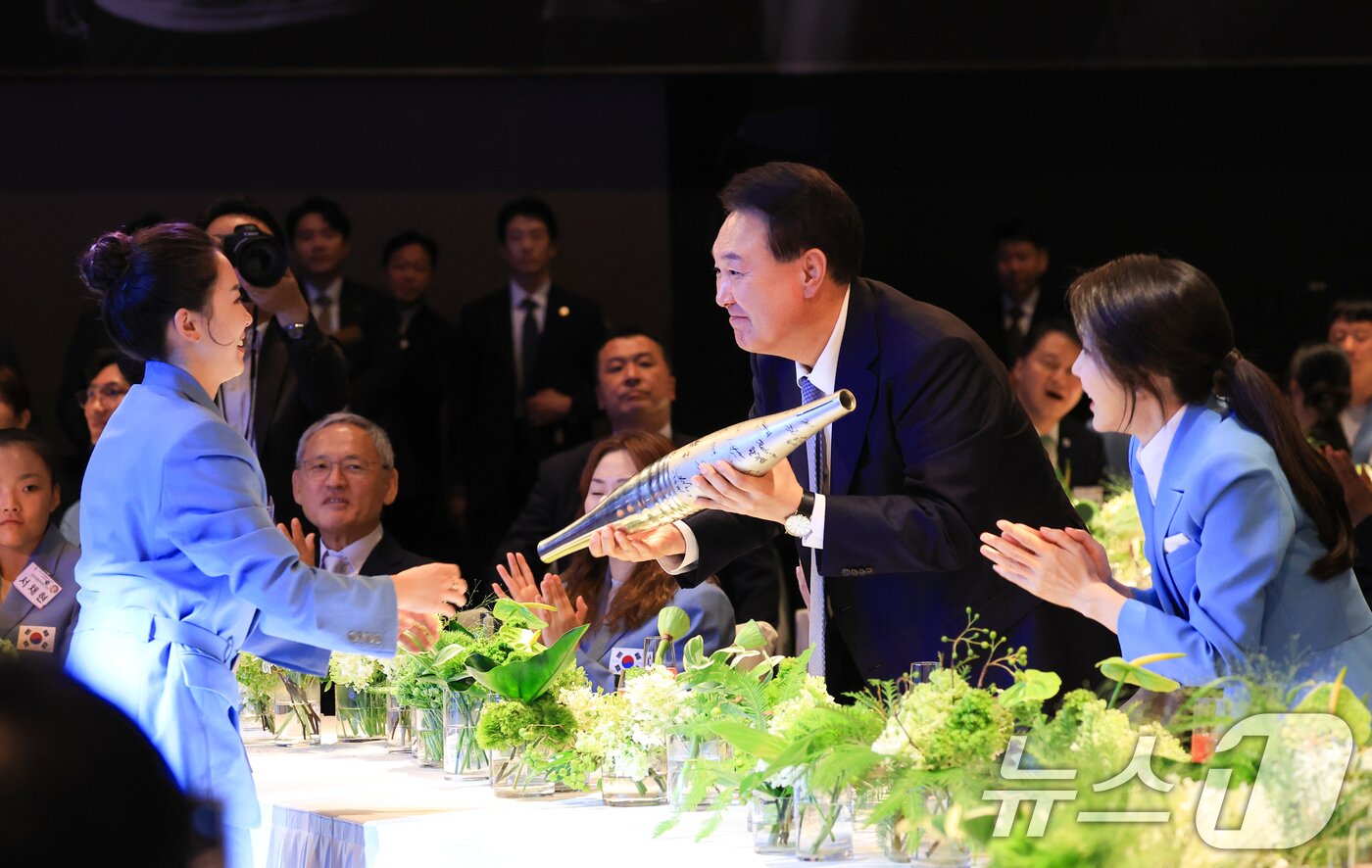 본문 이미지 - 윤석열 대통령과 김건희 여사가 22일 서울 중구 신라호텔에서 열린 &#39;2024 파리올림픽 선수단 격려 행사&#39;에서 탁구 전지희 선수로 부터 파리올림픽 선수들이 사인한 성화봉을 선물받고 있다. &#40;대통령실 제공&#41; 2024.8.22/뉴스1 ⓒ News1 송원영 기자
