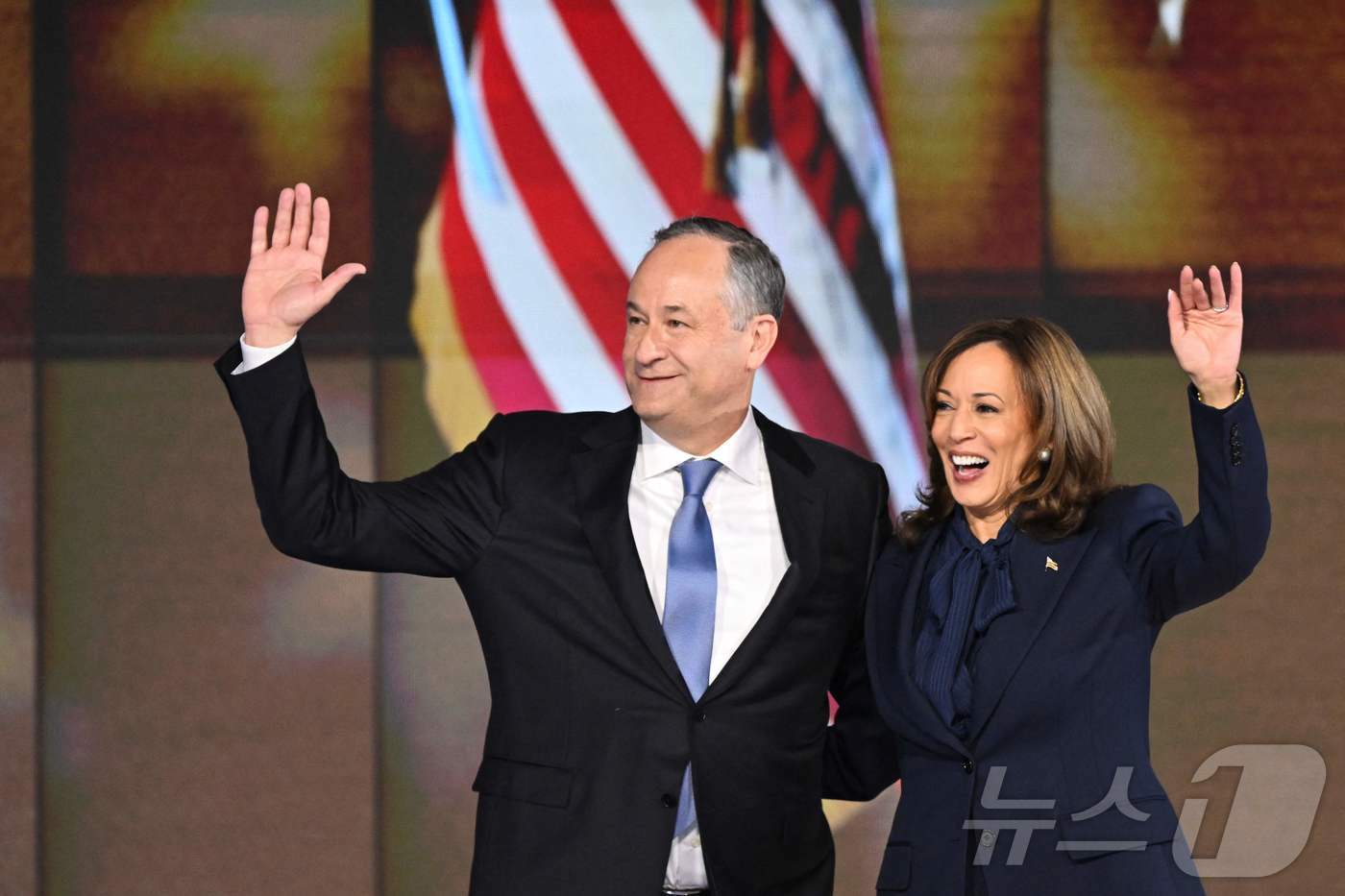 본문 이미지 - 카멀라 해리스 미국 부통령이 22일 (현지시간) 일리노이주 시카고의 유나이티드 센터에서 열린 민주당 전당대회 마지막 날 대선 후보 수락 연설을 마친 뒤 남편 더그 엠호프와 손을 들고 있다. 2024.08.23 ⓒ AFP=뉴스1 ⓒ News1 우동명 기자