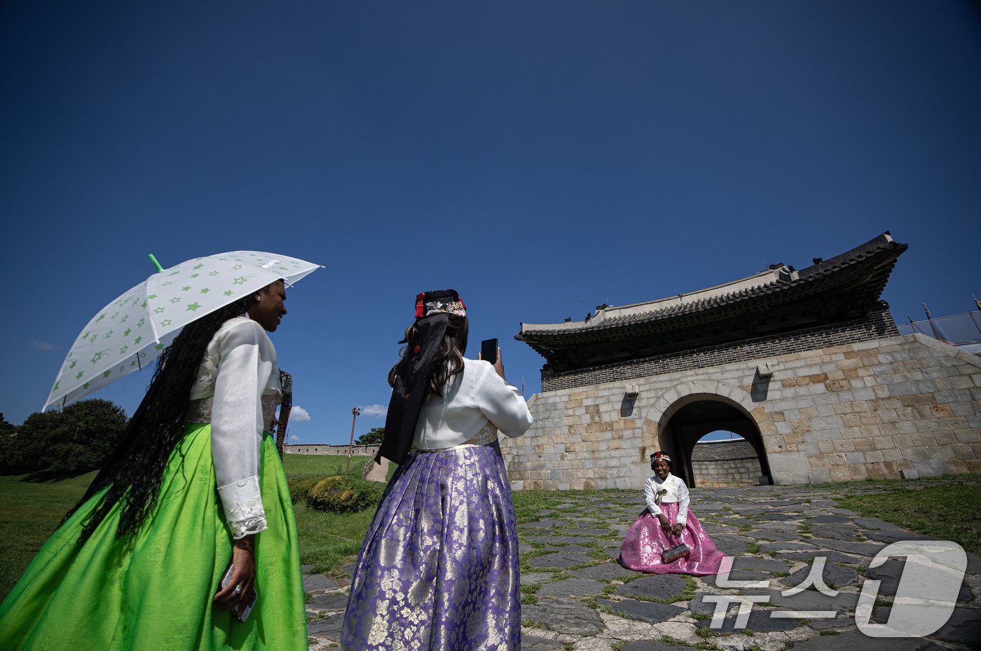본문 이미지 - 맑은 날씨를 보인 28일 오후 경기도 수원시 팔달구 세계문화유산 수원화성 창룡문을 찾은 외국인 관광객들이 파란 하늘을 배경으로 기념 촬영을 하고 있다. 2024.8.28/뉴스1 ⓒ News1 이재명 기자