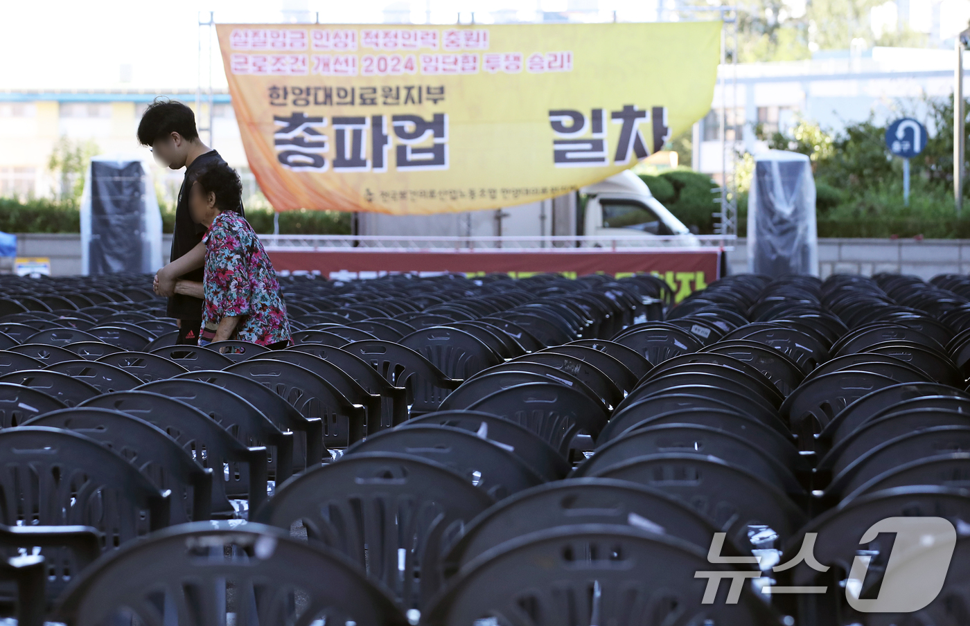 (서울=뉴스1) 오대일 기자 = 보건의료노조가 총파업을 사실상 철회한 29일 오전 서울 성동구 한양대병원에서 한 환자와 보호자가 파업 독려 현수막이 걸린 노조의 총파업 행사장 사이 …