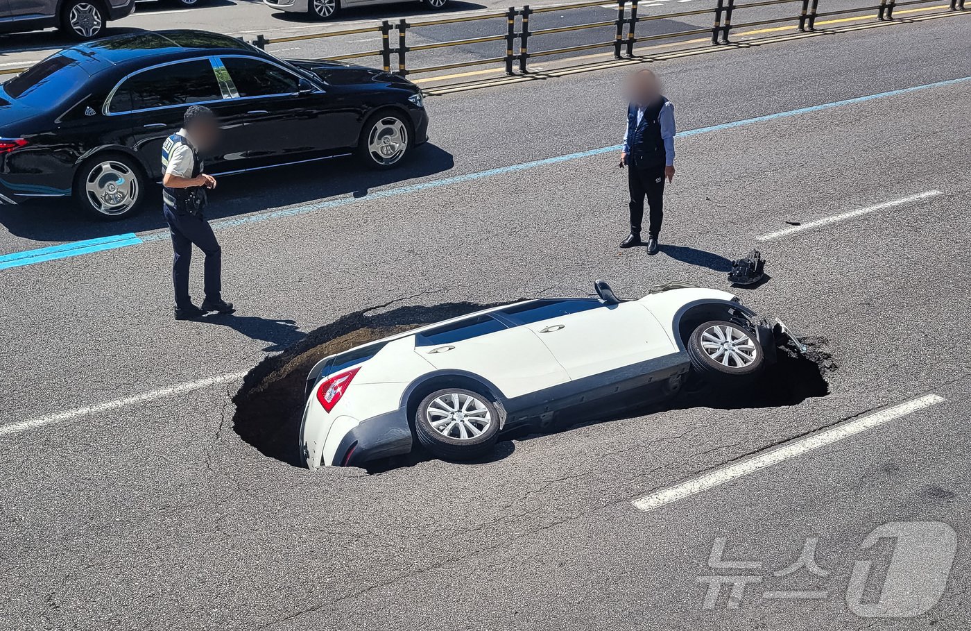 본문 이미지 - 29일 서울 서대문구 연희동의 한 차도에서 땅꺼짐 현상(싱크홀)이 발생해 승용차가 빠져 있다. 소방당국 등에 따르면 이번 사고로 승용차에 탑승 중이던 여성 A 씨(76)가 심폐소생술(CPR)을 받으며 병원으로 옮겨졌다. 운전자인 남성(82) 또한 크게 다쳐 병원으로 이송됐다. (온라인커뮤니티) 2024.8.29/뉴스1