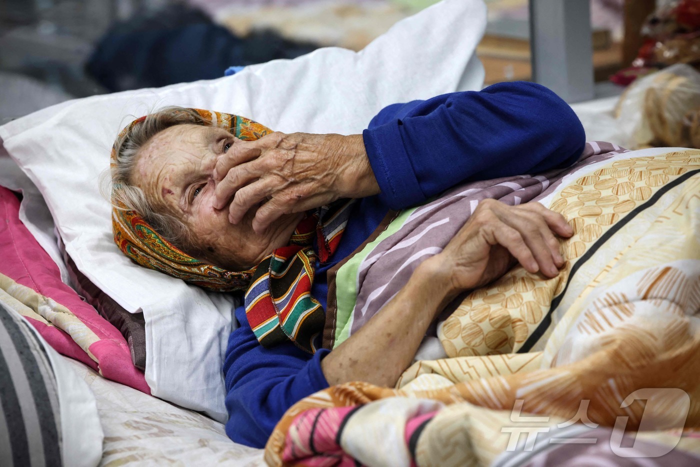 (러시아 AFP=뉴스1) 권진영기자 = 우크라이나의 역침공에 집을 떠난 한 러시아 노파가 29일(현지시간) 쿠르스크 모처의 민간인 대피시설 침대에 누워 무료한 시간을 보내고 있다. …