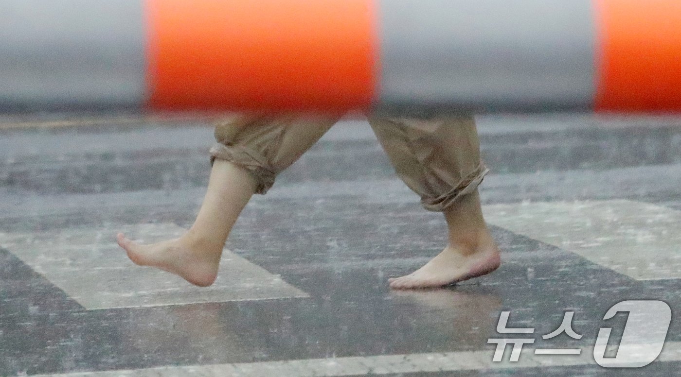 본문 이미지 - 전북 대부분 지역에 호우특보가 발효된 5일 전북자치도 전주시 백제대로에서 한 시민이 장대비가 쏟아지자 신발을 벗어 가방에 넣고 맨발로 걷고 있다. 2024.8.5/뉴스1 ⓒ News1 유경석 기자