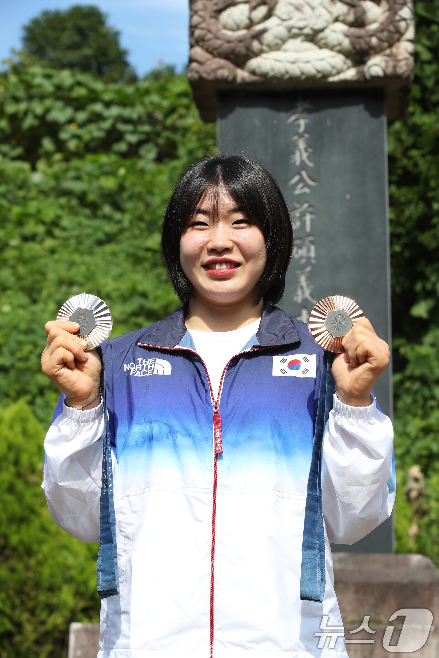 본문 이미지 - 2024 파리 올림픽에서 개인전 은메달과 단체전 동메달을 딴 유도 대표팀 허미미&#40;경북체육회&#41;가 6일 오전 대구 군위군 삼국유사면 화수리에 마련된 독립운동가이자 현조부인 허석 지사의 추모기적비를 찾아 참배를 앞두고 메달을 들어 보이고 있다. 2024.8.6/뉴스1 ⓒ News1 공정식 기자