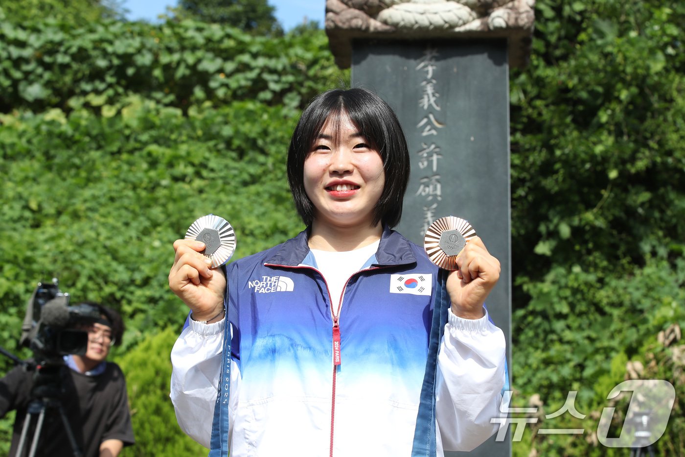 본문 이미지 - 2024 파리 올림픽에서 개인전 은메달과 단체전 동메달을 딴 유도 대표팀 허미미&#40;경북체육회&#41;가 6일 오전 대구 군위군 삼국유사면 화수리에 마련된 독립운동가이자 현조부인 허석 지사의 추모기적비를 찾아 참배를 앞두고 메달을 들어 보이고 있다. 2024.8.6/뉴스1 ⓒ News1 공정식 기자