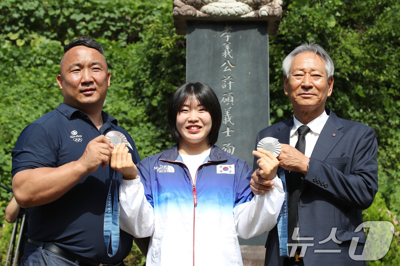 본문 이미지 - 2024 파리 올림픽에서 개인전 은메달과 단체전 동메달을 딴 유도 대표팀 허미미&#40;가운데·경북체육회&#41;가 6일 오전 대구 군위군 삼국유사면 화수리에 마련된 독립운동가이자 현조부인 허석 지사의 추모기적비를 찾아 참배를 앞두고 메달을 들어 보이고 있다. 왼쪽부터 경북체육회 김정훈 감독, 허미미, 김점두 경북체육회장. 2024.8.6/뉴스1 ⓒ News1 공정식 기자