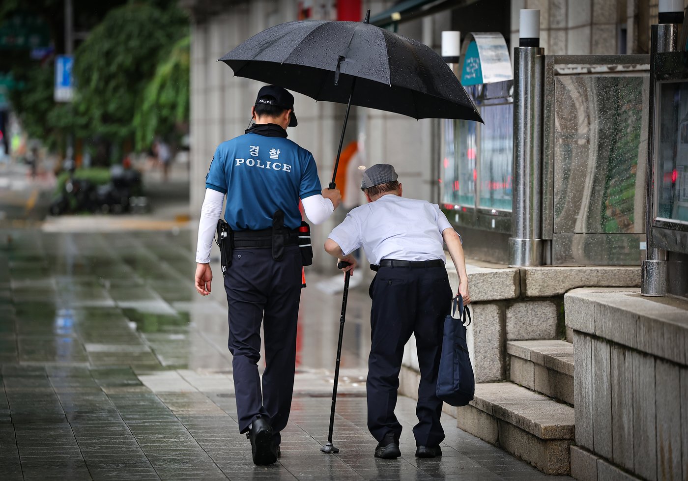 서울 종로구 광화문역 인근에서 경찰관이 한 어르신에게 우산을 씌어주고 있다. /뉴스1 ⓒ News1 김진환 기자