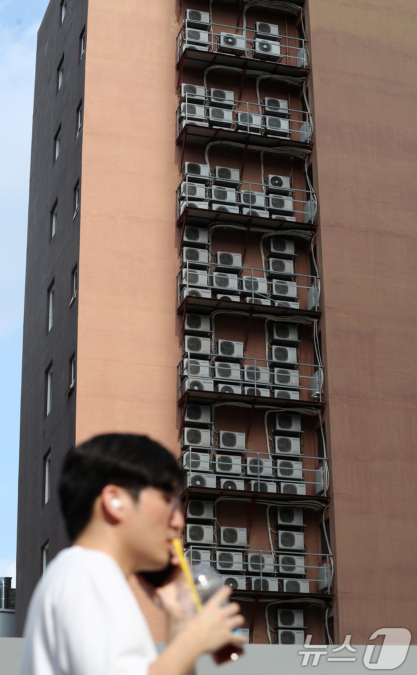 (서울=뉴스1) 박세연 기자 = 8일 서울 종로구의 에어컨실외기가 밀집된 한 건물외벽 앞으로 시원한 음료를 든 한 시민이 지나가고 있다.폭염과 열대야가 연일 기승을 부리는 가운데 …