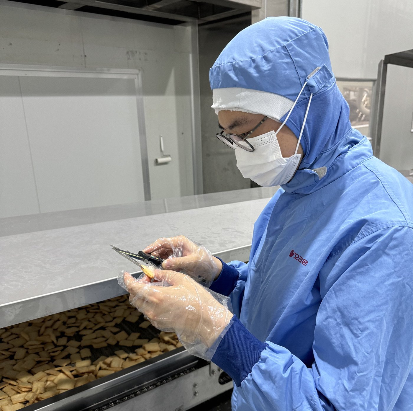 본문 이미지 - 김남호 글로벌연구소 선임연구원이 오리온농협 밀양공장에서 뉴룽지의 크기 등을 검수하는 모습(오리온 제공)