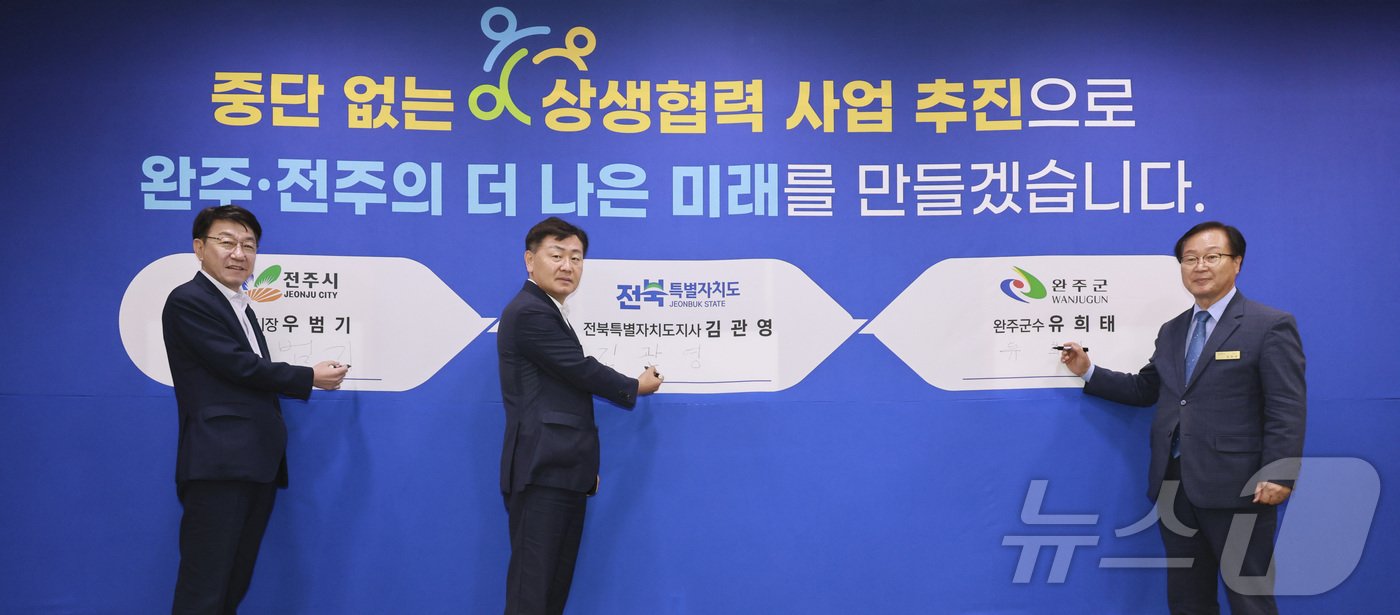 본문 이미지 - 11일 ‘완주·전주 상생협력사업 12차 협약식’이 열린 가운데 김관영 도지사와 우범기 전주시장, 유희태 완주군수가 '중단없는 상생협력 사업 추진' 다짐판에 직접 서명하고 있다.(전북자치도 제공)/뉴스1 