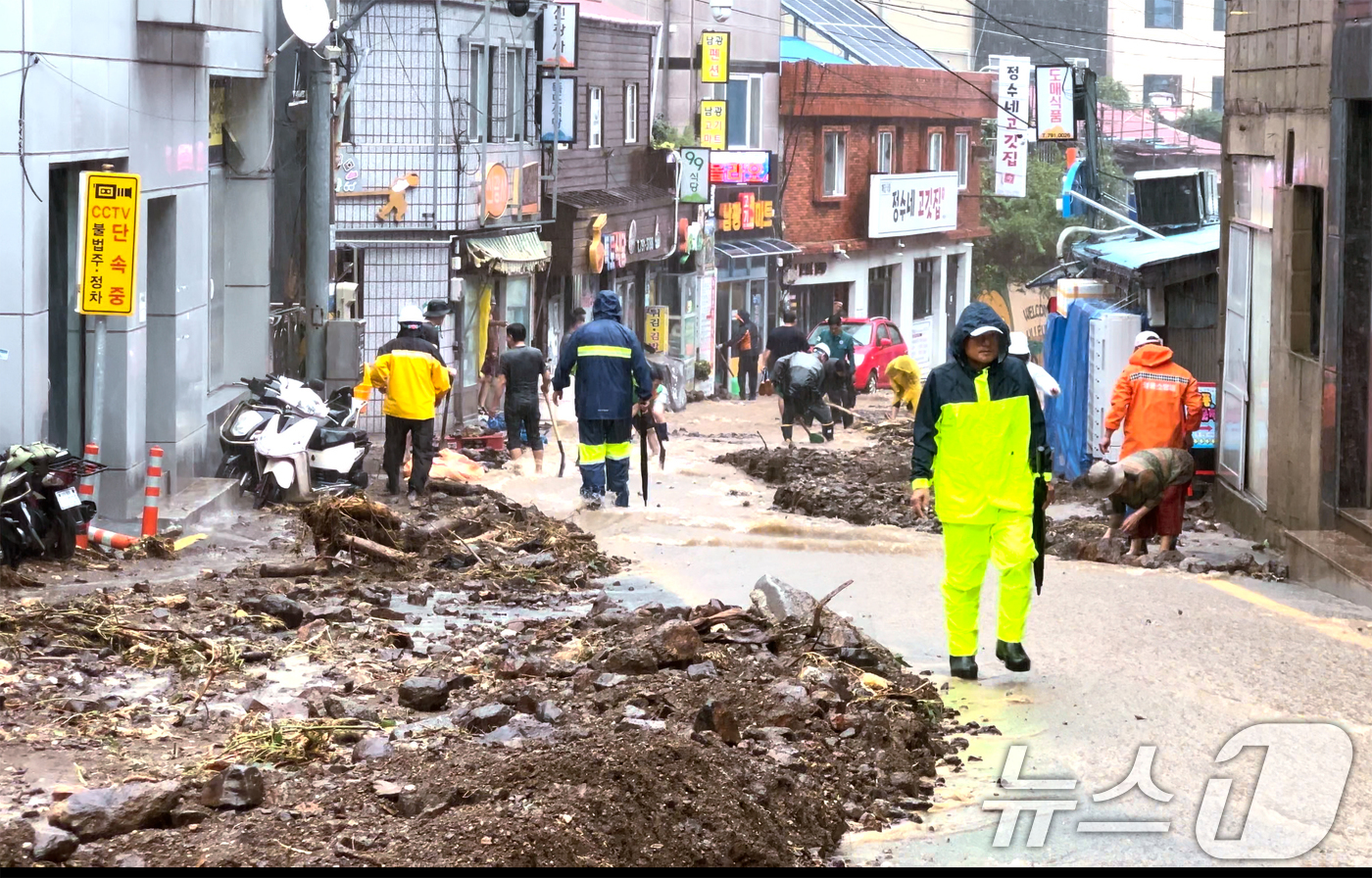 (울릉=뉴스1) 최창호 기자 = 12일 경북 울릉군 울릉읍 지역에 국지성 호우로 인한 피해가 발생한 가운데 주민들이 도로를 덮은 토사를 치우고 있다. (울릉군제공) 2024.9.1 …