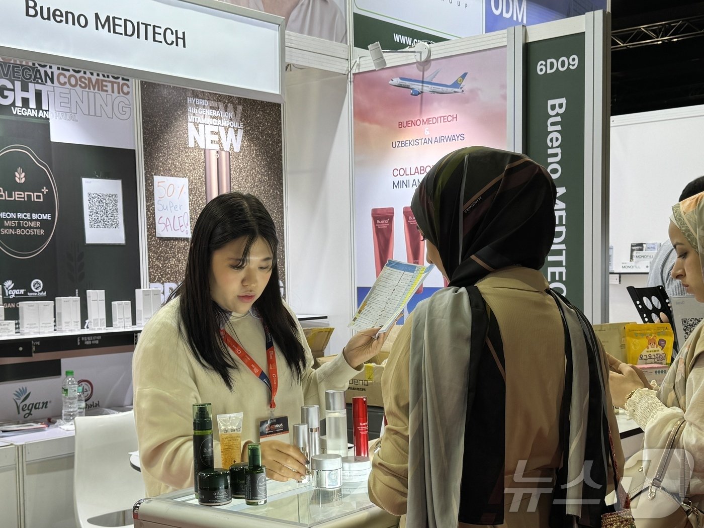 본문 이미지 - 미하스&#40;MIHAS&#41; 박람회에서 말레이시아 방문객이 한국 화장품 부스에서 설명을 듣고 있다.