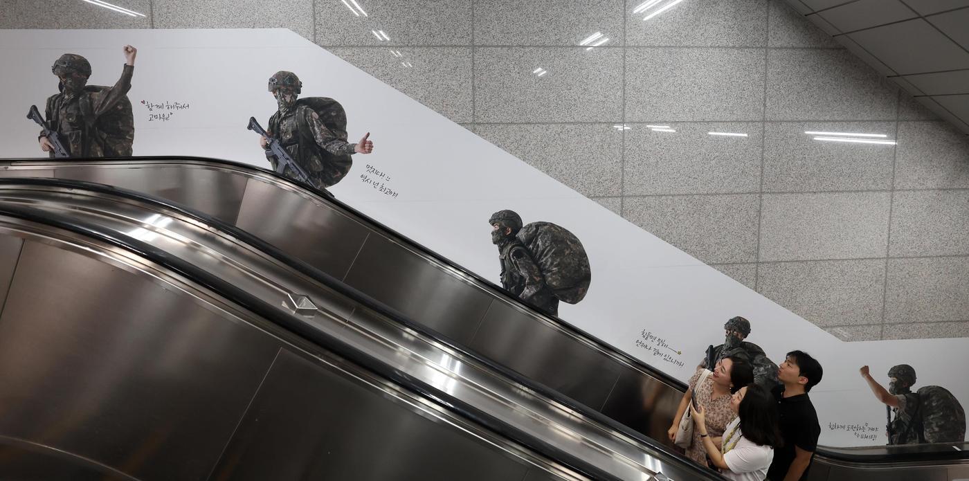 본문 이미지 - 시민들이 신용산역 1번 출구 에스컬레이터에 설치된 광고를 보며 에스컬레이터를 이용하고 있다.(국방부 제공)