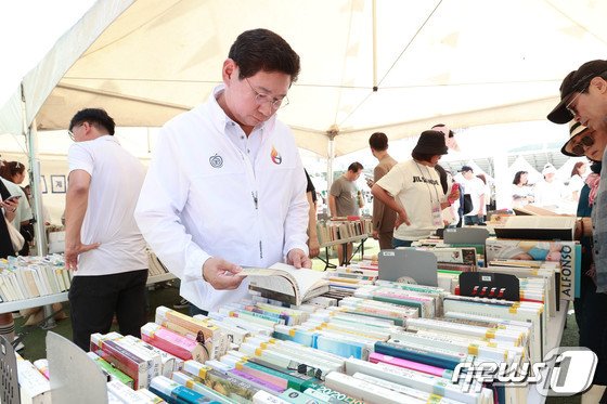 지난해 9월 열린 북 페스티벌에서 이상일 시장이 도서관 제적도서를 1000원에 파는 &#39;북 세일&#39; 부스에서 시민들과 함께 도서를 살펴보고 있는 모습.&#40;용인시 제공&#41;