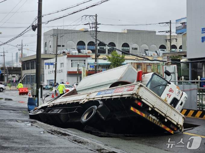 본문 이미지 - 21일 오전 8시45분께 부산 사상구 한 도로에서 가로 10m, 세로 5m, 깊이 8m 가량의 대형 땅꺼짐 현상(싱크홀)이 발생해 도로에서 배수 지원을 하던 삼락119안전센터 배수 차량과 5톤 트럭이 빠져있다. (부산소방재난본부 제공) 2024.9.21/뉴스1 ⓒ News1 윤일지 기자
