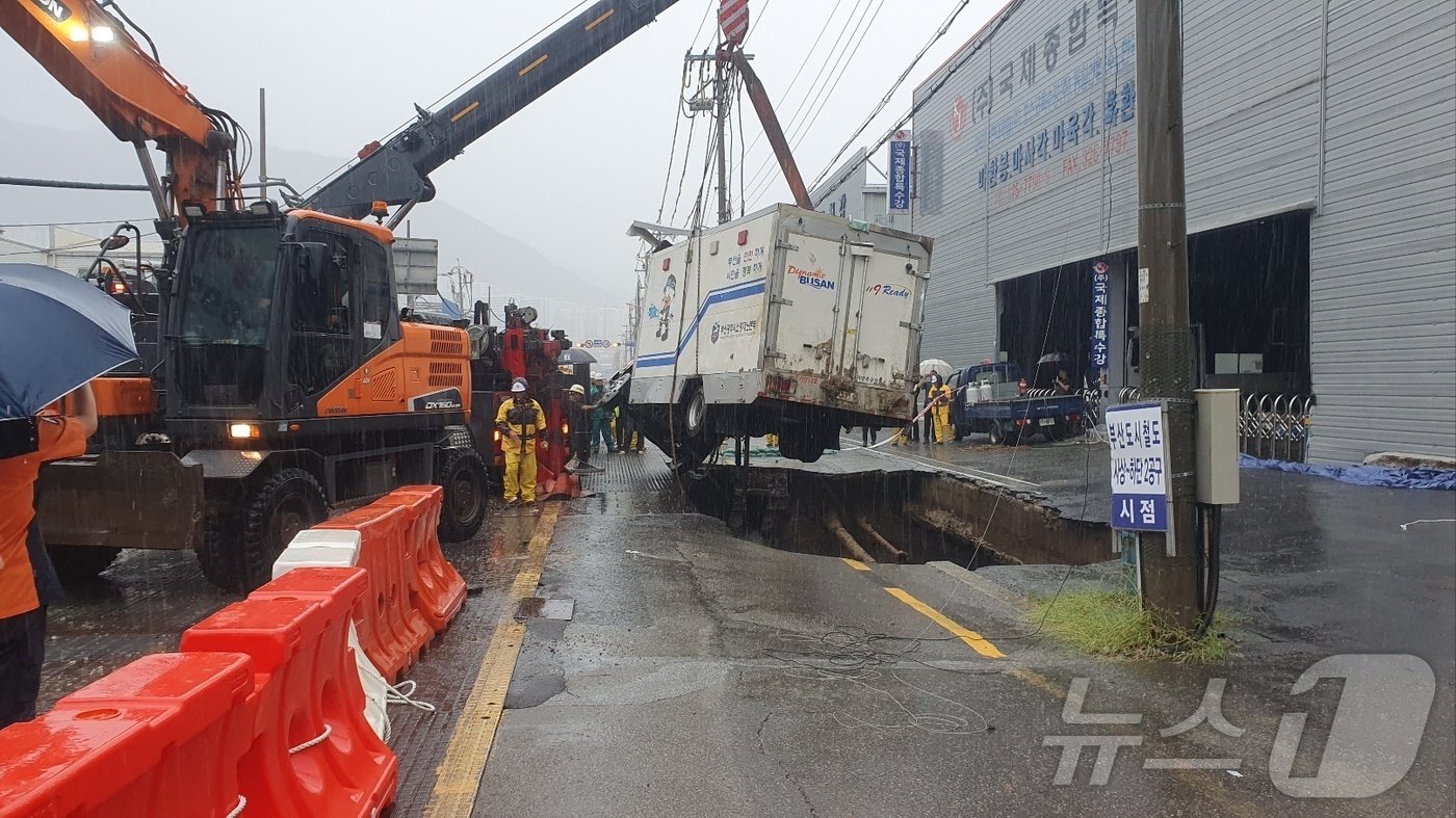 21일 부산 사상구 한 도로에서 발생한 땅 꺼짐 현상으로 구멍에 빠진 5톤 트럭이 인양되고 있다.&#40;부산소방재난본부 제공&#41;