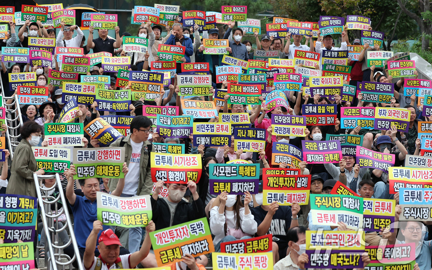 (서울=뉴스1) 장수영 기자 = 한국주식투자자연합회 회원 및 개인투자자들이 21일 오후 서울 중구 서울역 광장에서 금융투자소득세 도입을 반대하는 피켓을 들어보이고 있다. 2024. …