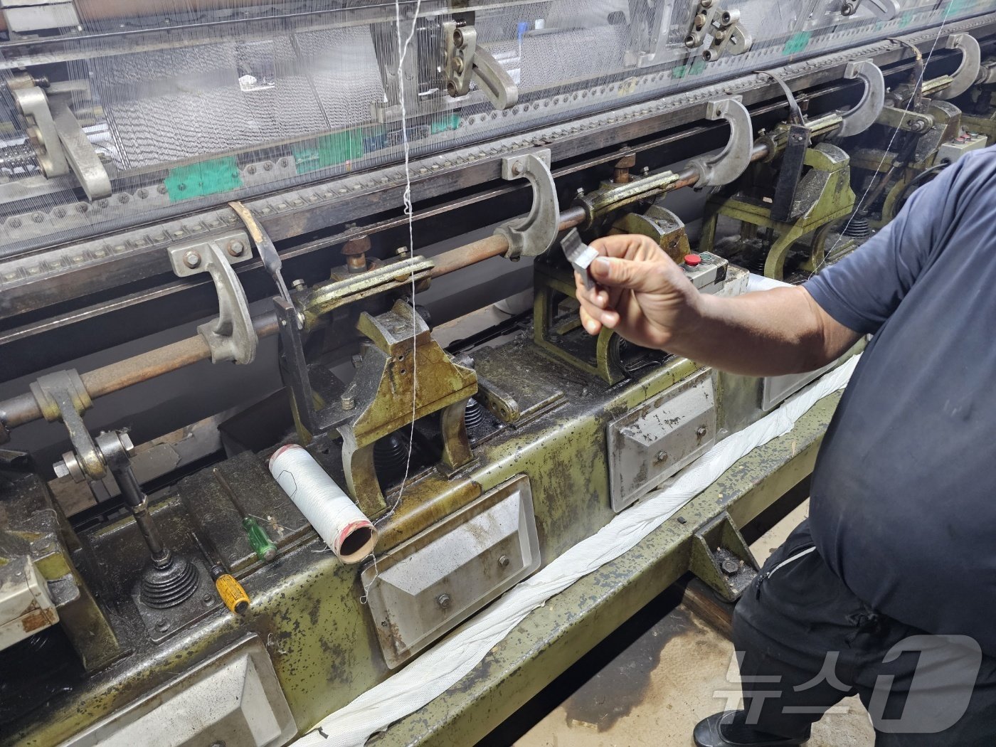 본문 이미지 - 김해시 이동에서 섬유 원단 제조 공장을 운영하는 이상주씨가 물에 잠긴 기계를 만지고 있다. 2024.9.23 ⓒ 뉴스1 박민석 기자