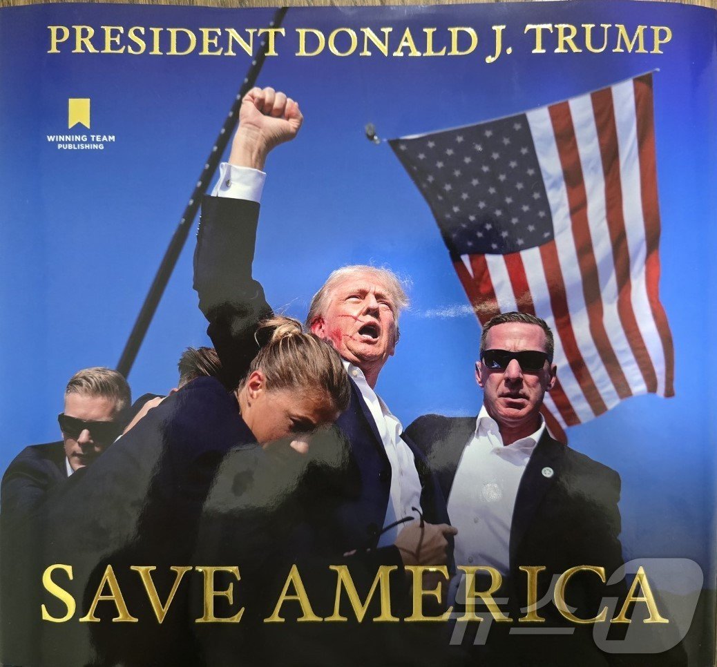 도널드 트럼프 전 미국 대통령이 이달 3일&#40;현지시간&#41; 출간한 화보집 &#39;세이브 아메리카&#40;Save America&#41;&#39; 표지. 지난 7월 펜실베이니아 유세 도중 총격으로 오른쪽에 귀에 관통상을 입었음에도 주먹을 불끈 들어올리며 &#39;싸우자&#40;Fight&#41;&#39;를 외치는 장면이다. 총 360쪽 분량이며, 99달러&#40;약 13만원&#41;에 판매한다.