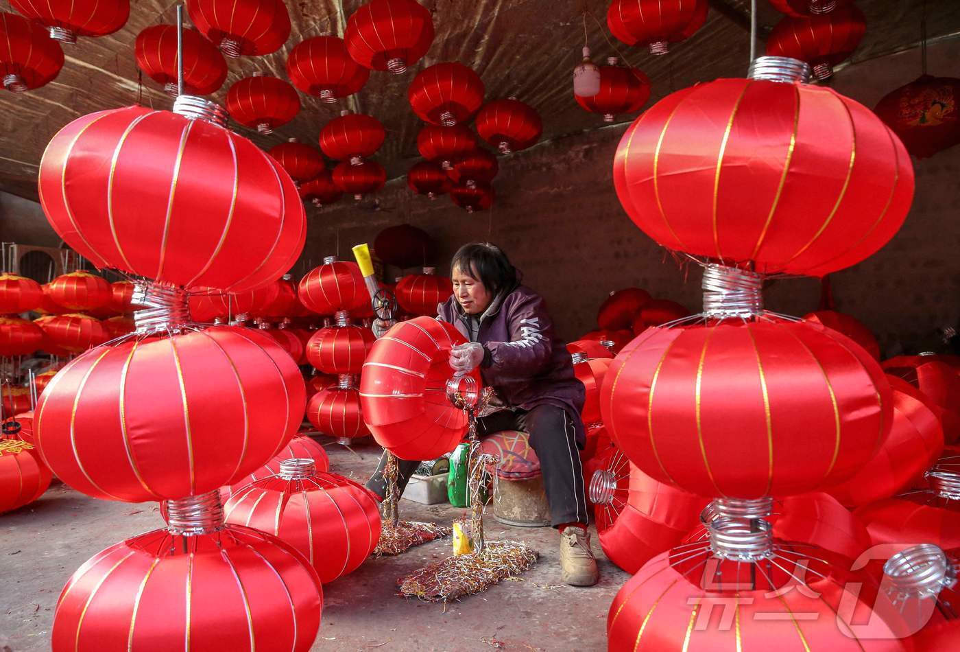 본문 이미지 - 2024년 12월 30일에 내년 뱀의 해를 앞두고 중국 중부 산시성 윈청시 양자오 마을의 한 공장에서 한 여성이 붉은등을 만들고 있다. ⓒ AFP=뉴스1