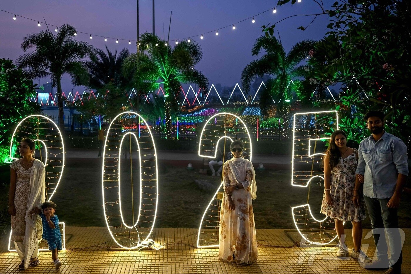 본문 이미지 - 새해 전야인 2024년 12월 31일 인도 뭄바이의 조명이 켜진 바다 산책로에서 사람들이 사진을 찍고 있다. ⓒ AFP=뉴스1