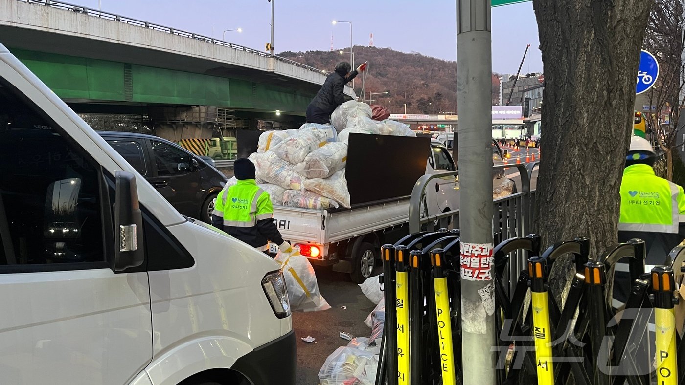 10일 오전 7시 30분쯤 서울 용산구 한남동 한남대로에서 미화원들이 차에 올라타 쓰레기를 정리하고 있다. 2025.1.10/ 뉴스1