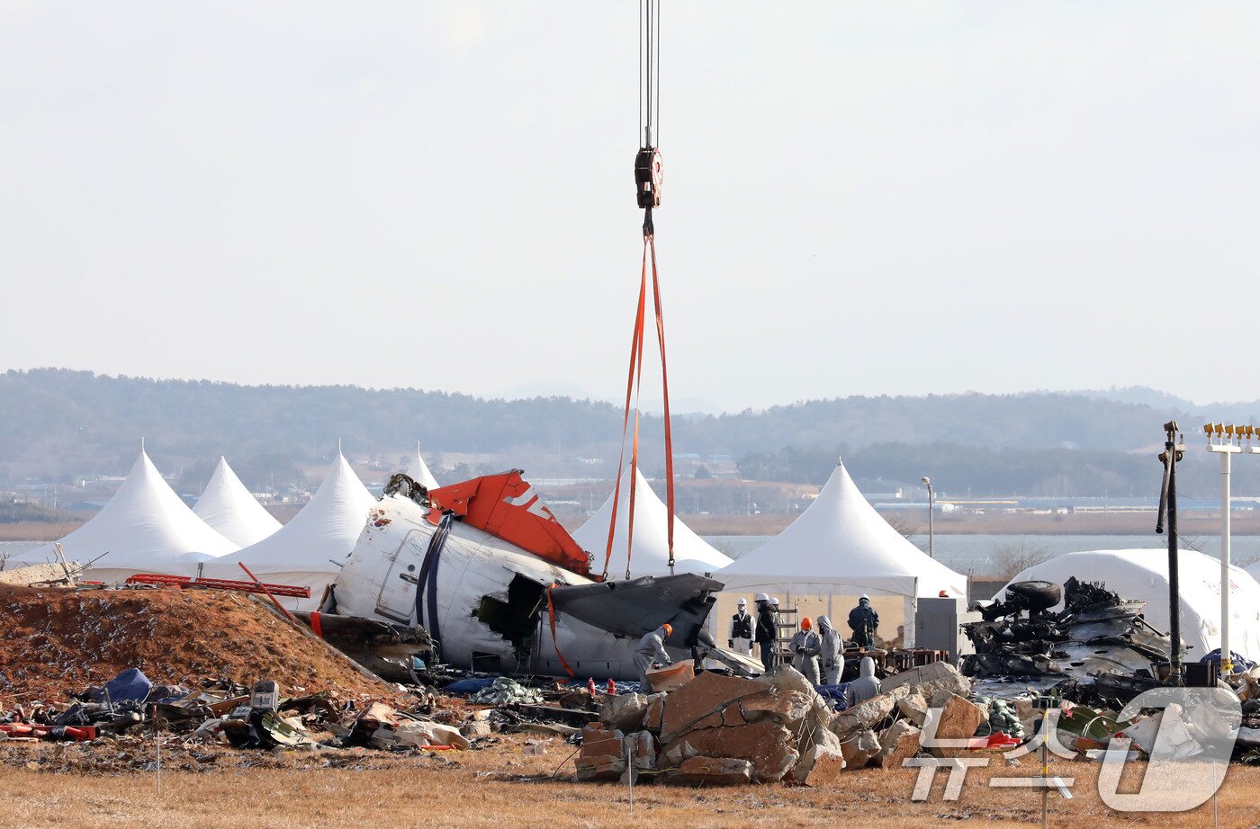 본문 이미지 - 15일 오전 전남 무안국제공항 참사 현장에서 항공·철도사고 조사위원회 관계자들이 기체 잔해 수습을 위해 기중기에 걸고 있다. 2025.1.15/뉴스1 ⓒ News1 박지현 기자