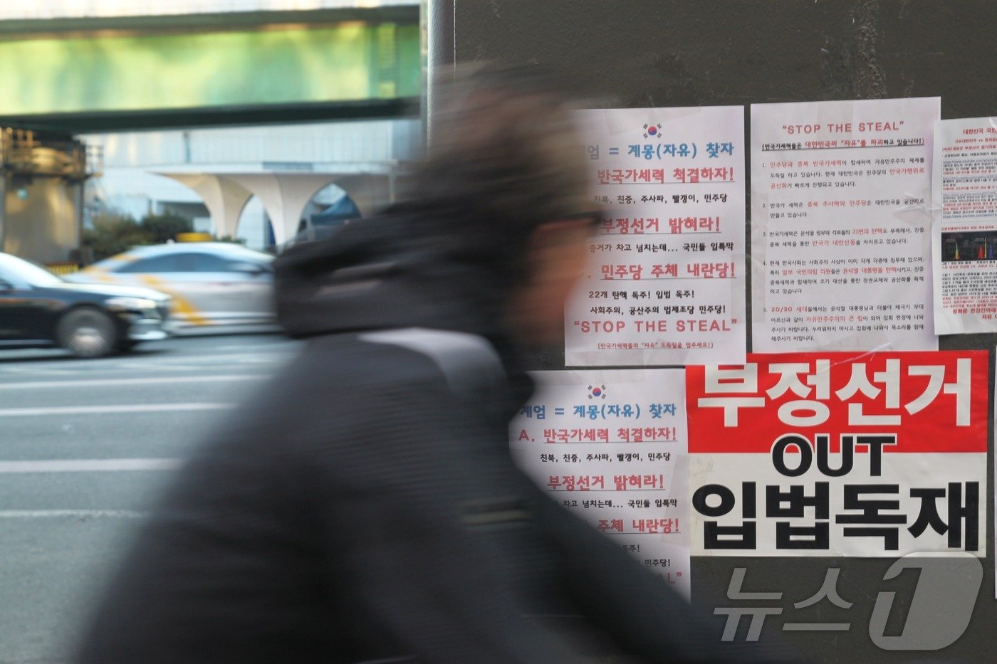 본문 이미지 - 윤석열 대통령이 체포된 15일 오후, 자전거를 탄 시민이 한남대로 육교 기둥에 붙은 윤석열 대통령 지지자들의 전단을 바라보고 있다.2025.01.15/뉴스1 ⓒ 뉴스1 김민재 기자
