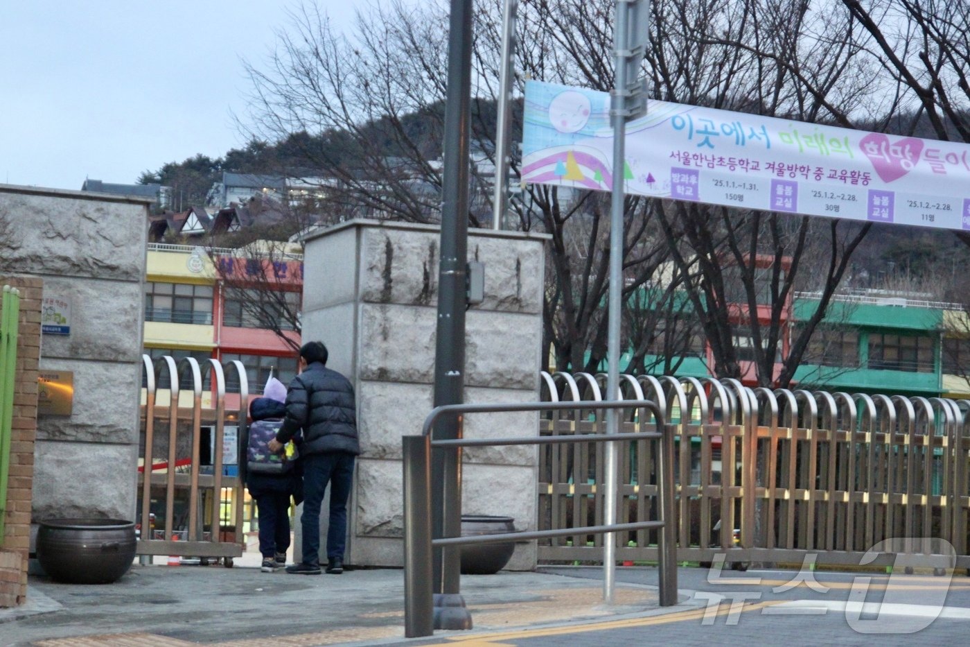 본문 이미지 - 윤석열 대통령이 체포된 다음날인 16일, 서울 용산구 한남동에 위치한 한남초등학교에서 한 남성이 아이를 바래다주고 있다.2025.1.16/뉴스1 ⓒ 뉴스1 김민재 기자