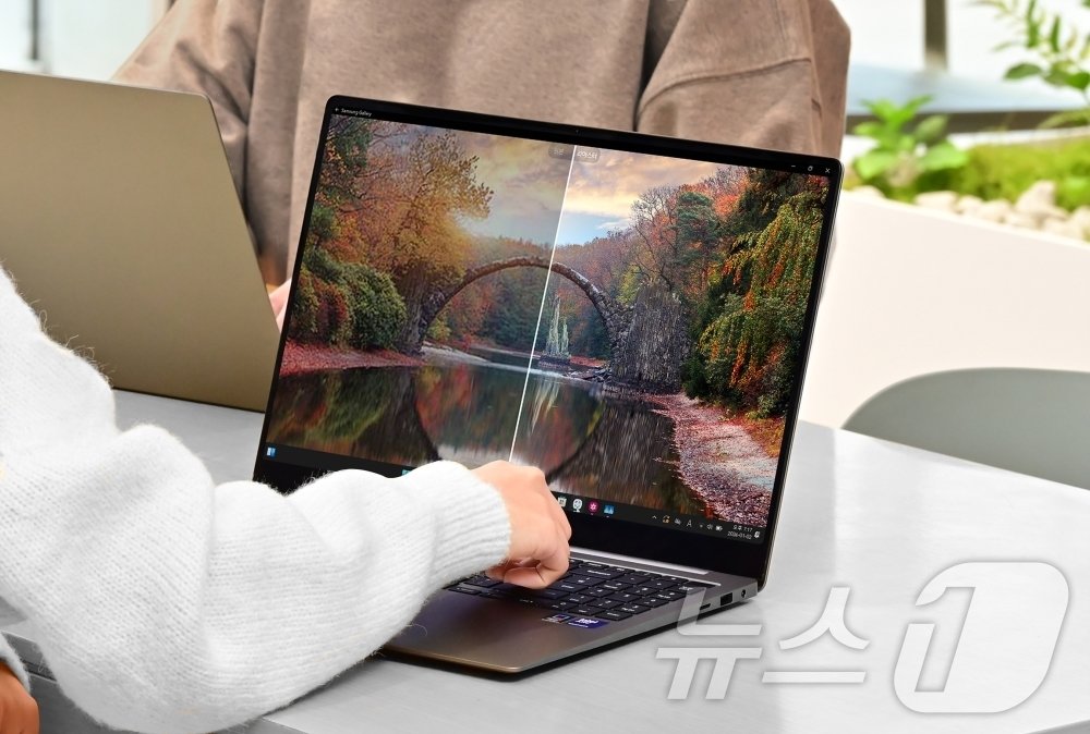 본문 이미지 - 삼성전자 모델이 AI PC '갤럭시 북5 시리즈'의 '사진 리마스터' 기능을 체험하는 모습(삼성전자 제공). ⓒ 뉴스1