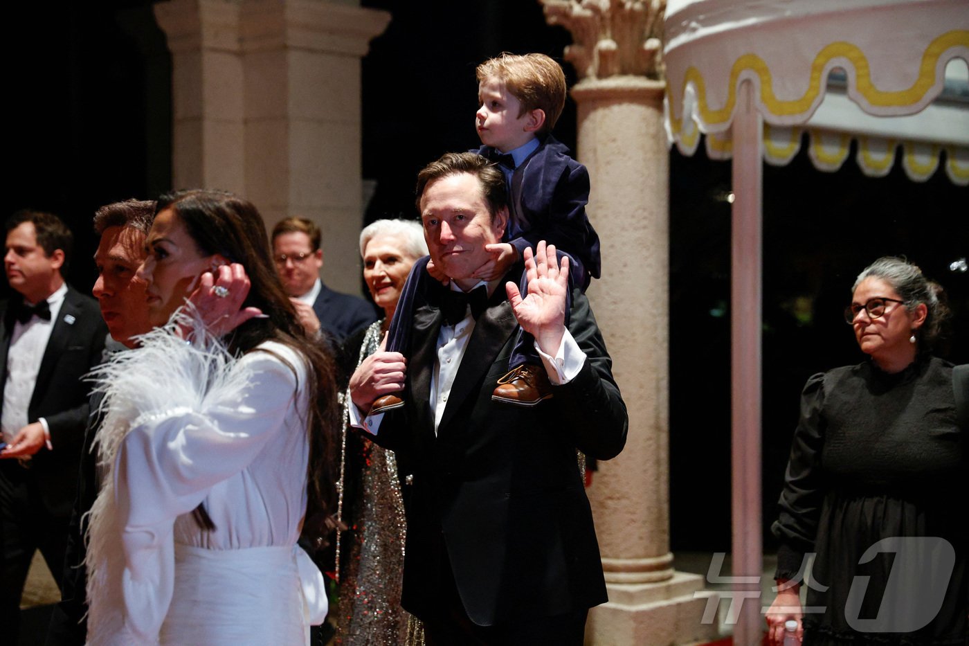 본문 이미지 - 2024년 12월 31일&#40;현지시간&#41; 도널드 트럼프 미국 대통령 당선인의 플로리다주 팜비치의 개인 리조트 마러라고에서 열린 새해 전야 파티에서 일론 머스크 테슬라 최고경영자&#40;CEO&#41;가 자신의 어린 아들을 목마를 태운 채 등장하고 있다. 2024.12.31. ⓒ 로이터=뉴스1 ⓒ News1 조소영 기자