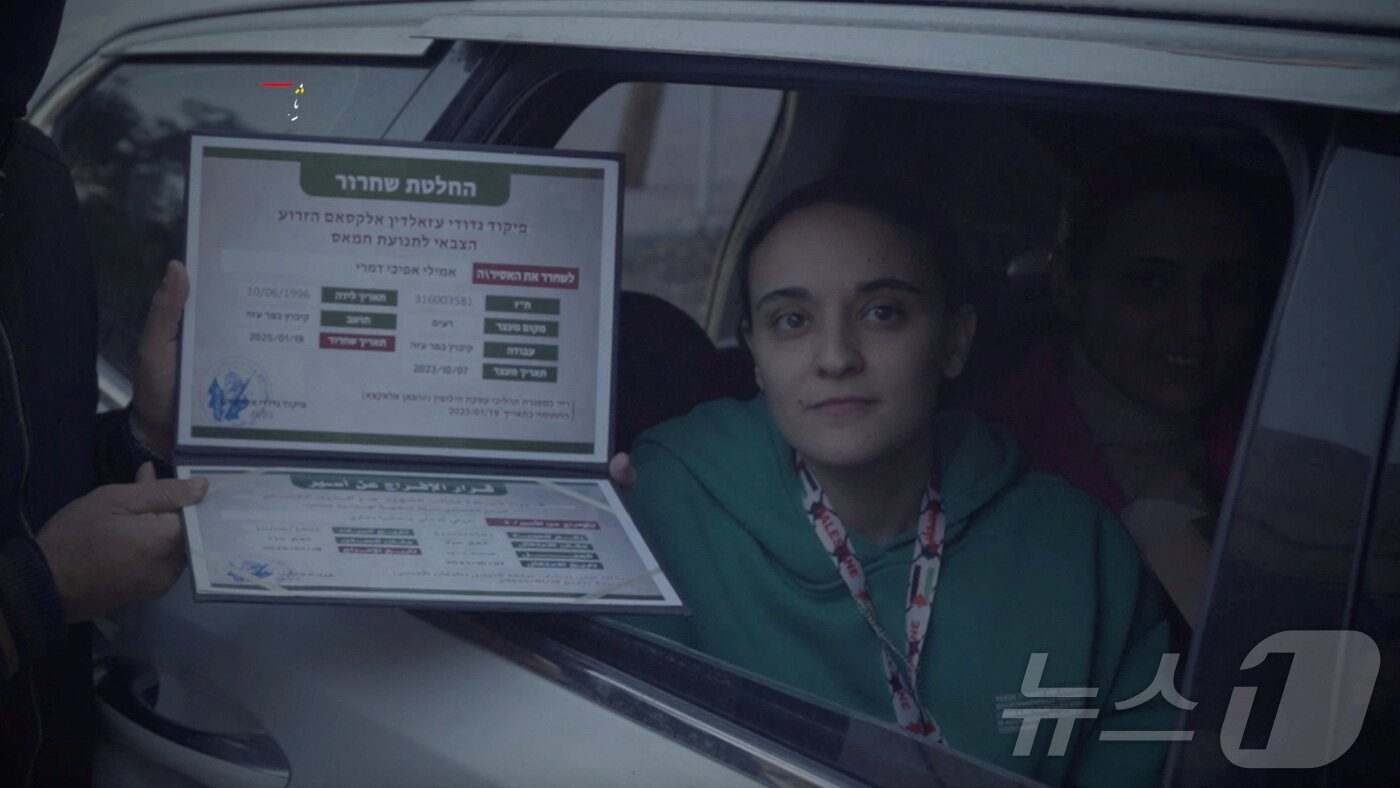 본문 이미지 - 팔레스타인 무장 정파 하마스에 억류됐다가 19일(현지시간) 풀려난 에밀리 다마리가 하마스가 증정한 증명서와 함께 사진을 찍고 있다. 2025.01.19 ⓒ 로이터=뉴스1 ⓒ News1 정지윤 기자