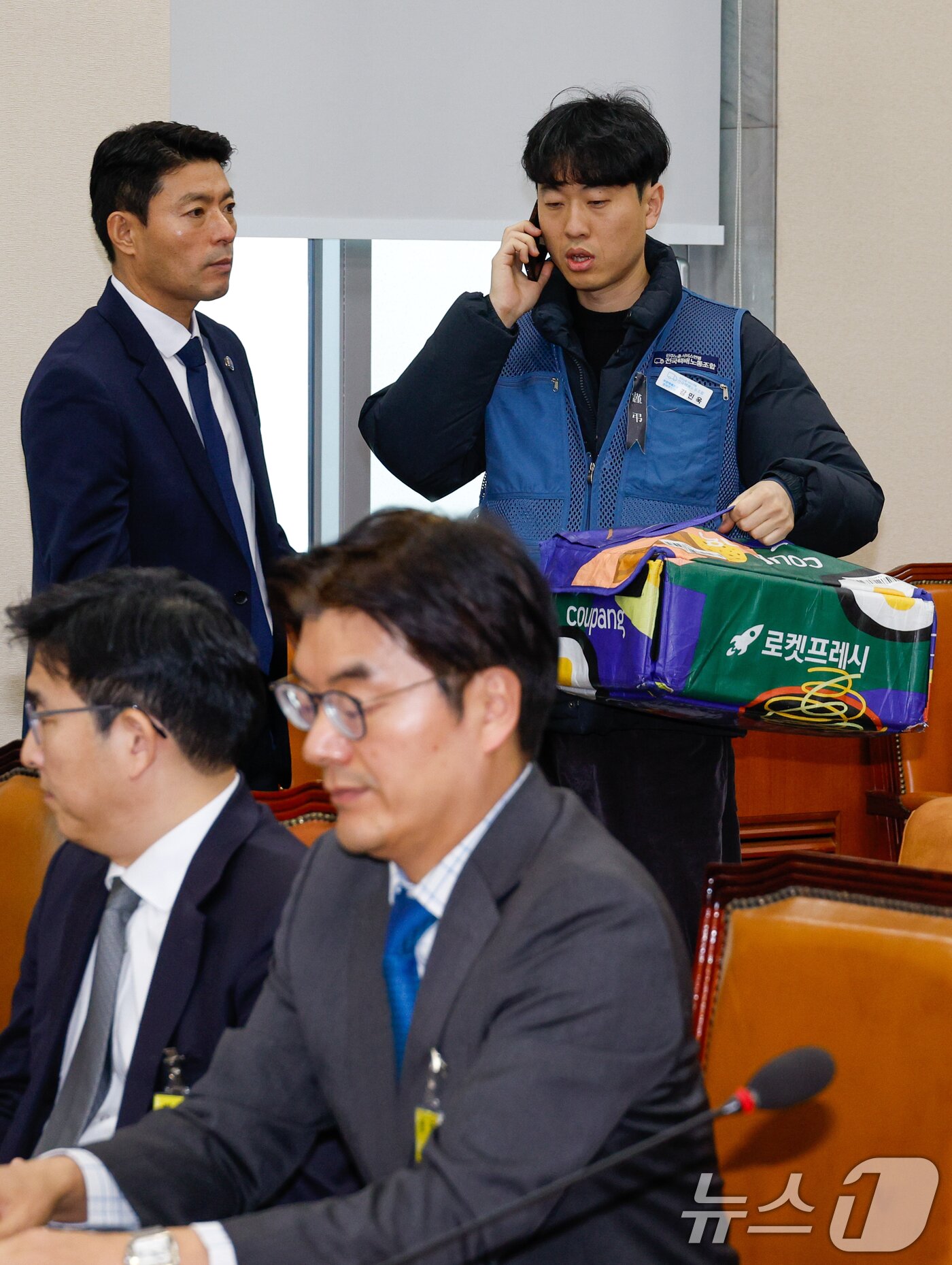 본문 이미지 - 강민욱 택배노동자과로사대책위 집행위원장이 21일 서울 여의도 국회 환경노동위원회에서 열린 쿠팡 택배노동자 심야노동 등 근로조건 개선을 위한 청문회에 출석하며 쿠팡 로켓프레시백을 들고 있다. 2025.1.21/뉴스1 ⓒ News1 안은나 기자