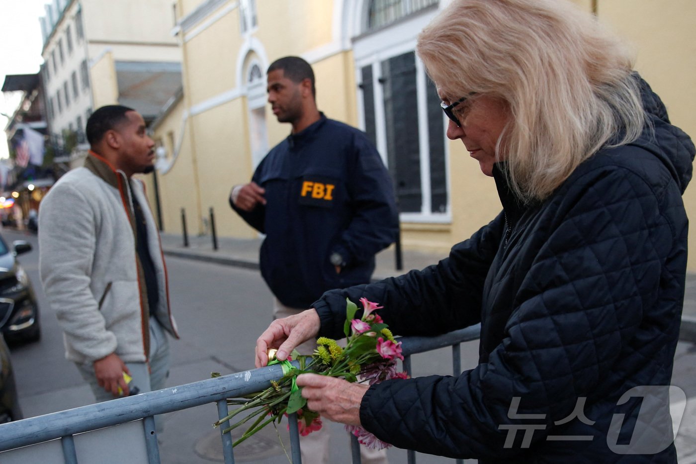 본문 이미지 - 1일&#40;현지시간&#41; 미국 루이지애나주 뉴올리언스에서 새해맞이 행사 중 트럭을 몰고 군중을 향해 돌진해 사람들이 사망한 사건이 발생한 후 사만다 맥거번이 꽃다발을 보안 장벽에 묶고 있다. ⓒ 로이터=뉴스1 ⓒ News1 류정민 특파원