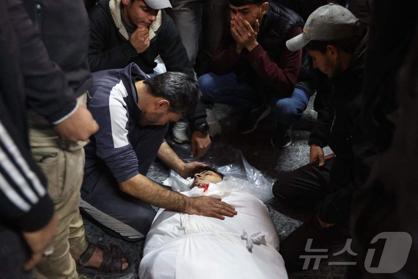 본문 이미지 - 2일(현지시간) 팔레스타인 가자 지구 병원에서 주민들이 하마스와 전쟁 중인 이스라엘 군의 포격을 받아 숨진 희생자를 안고 오열하고 있다. 2025.01.03 ⓒ AFP=뉴스1 ⓒ News1 우동명 기자