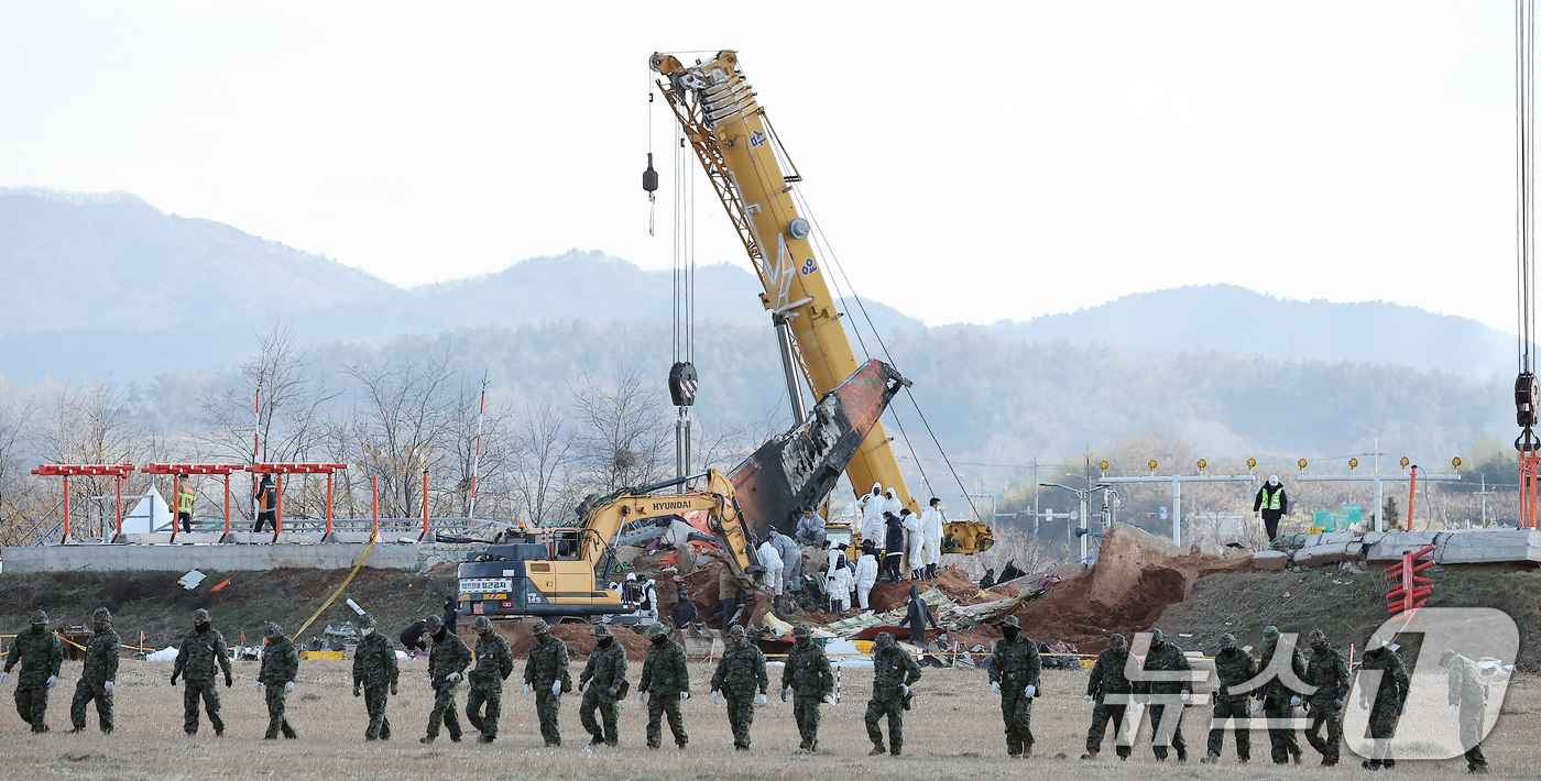 (무안=뉴스1) 김진환 기자 = 제주항공 여객기 참사 7일째인 4일 오후 전남 무안국제공항 참사 현장에서 특전사 대원들의 수색 작업 뒤로 방위각시설(로컬라이저)에서 엔진 인양 작업 …