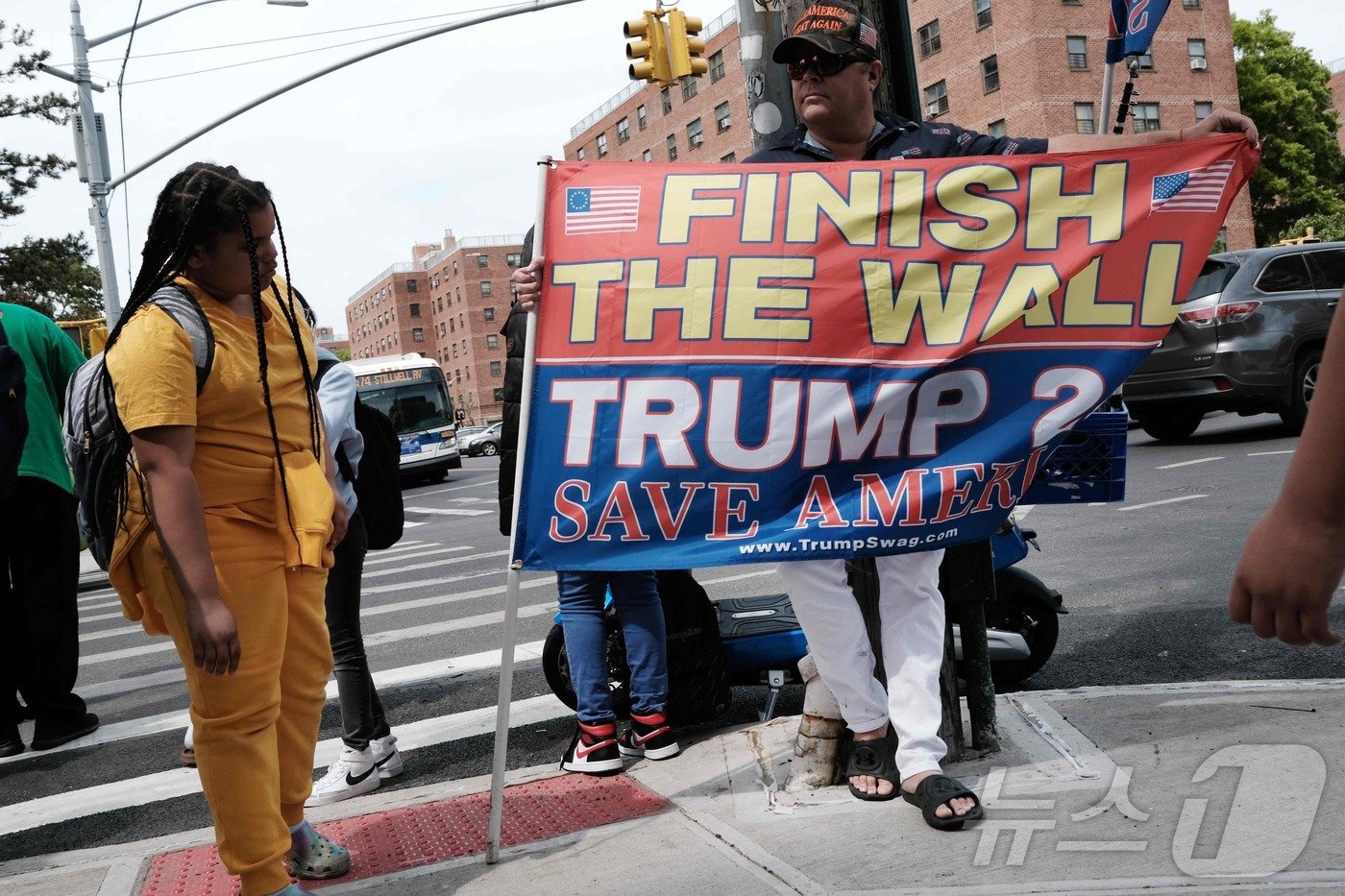 본문 이미지 - 미국 뉴욕시에서 한 시위자가 "국경 장벽을 완성해라＂ ＂트럼프가 미국을 구한다＂는 표어가 적힌 깃발을 들고 있다. 2023.05.16/ ⓒ AFP=뉴스1 ⓒ News1 권진영 기자