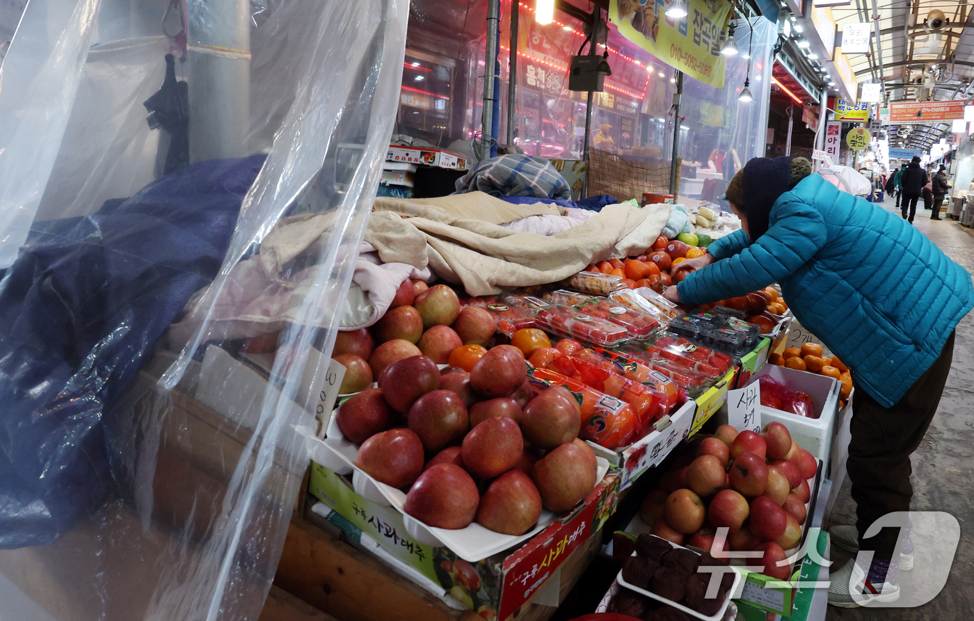 (서울=뉴스1) 김명섭 기자 = 7일 서울 서대문구 영천시장에서 상인이 한파소식에 과일에 이불을 덮어 놓고 살펴보고 있다.전라지역에 최대 40㎝에 달하는 폭설이 예상되면서, 설 연 …