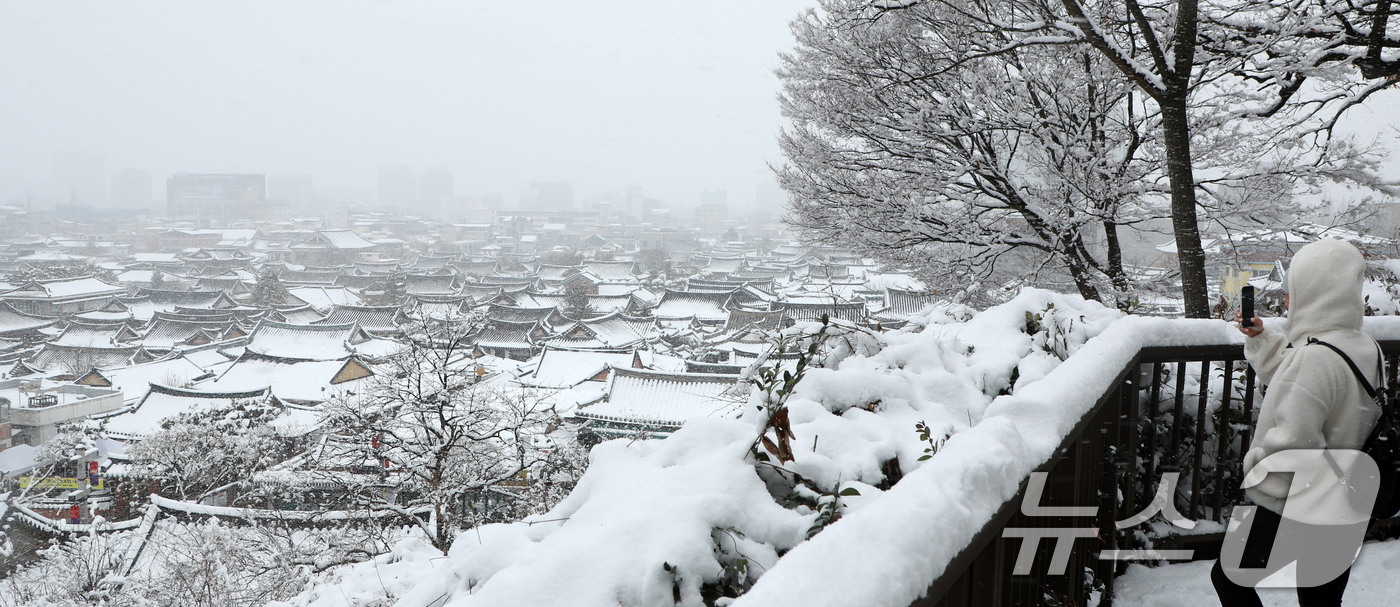 (전주=뉴스1) 유경석 기자 = 전북지역 곳곳에 대설주의보가 발효된 8일 전북자치도 전주시 한옥마을 오목대 산책로에서 한 외국인이 눈 덮인 한옥마을을 찍고 있다. 2025.1.8/ …