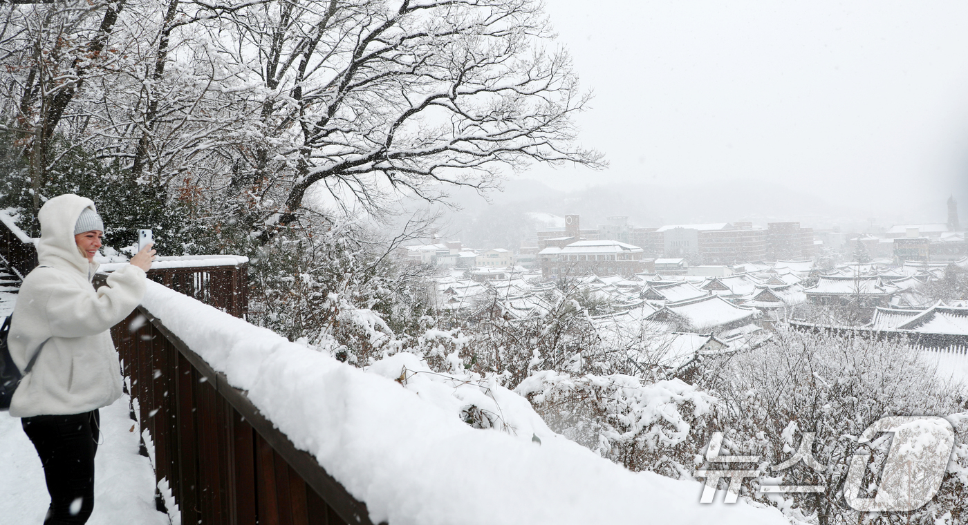 (전주=뉴스1) 유경석 기자 = 전북지역 곳곳에 대설주의보가 발효된 8일 전북자치도 전주시 한옥마을 오목대 산책로에서 한 외국인이 눈 덮인 한옥마을을 찍고 있다. 2025.1.8/ …