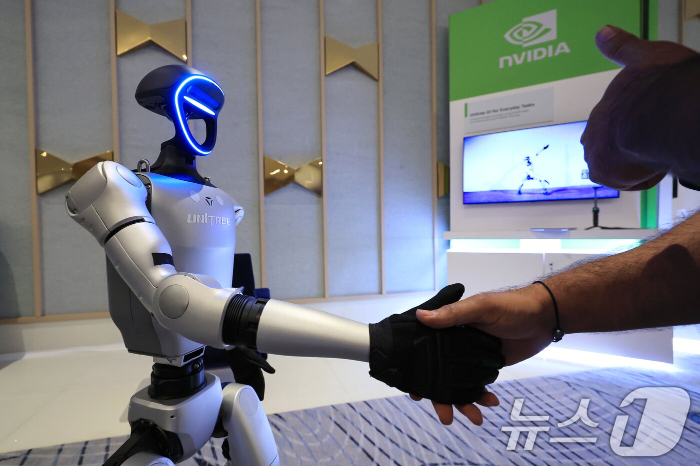 본문 이미지 - 세계 최대 가전·정보기술(IT) 전시회 CES 2025 개막일인 7일(현지시간) 젠슨 황 엔비디아 최고경영자(CEO) 글로벌 기자간담회가 열린 미국 네바다주 라스베이거스 퐁텐블루 호텔에 마련된 엔비디아 전시관에서 휴머노이드 로봇 유니트리 G1이 관람객과 악수하고 있다. (공동취재) 2025.1.8/뉴스1 ⓒ News1 신웅수 기자