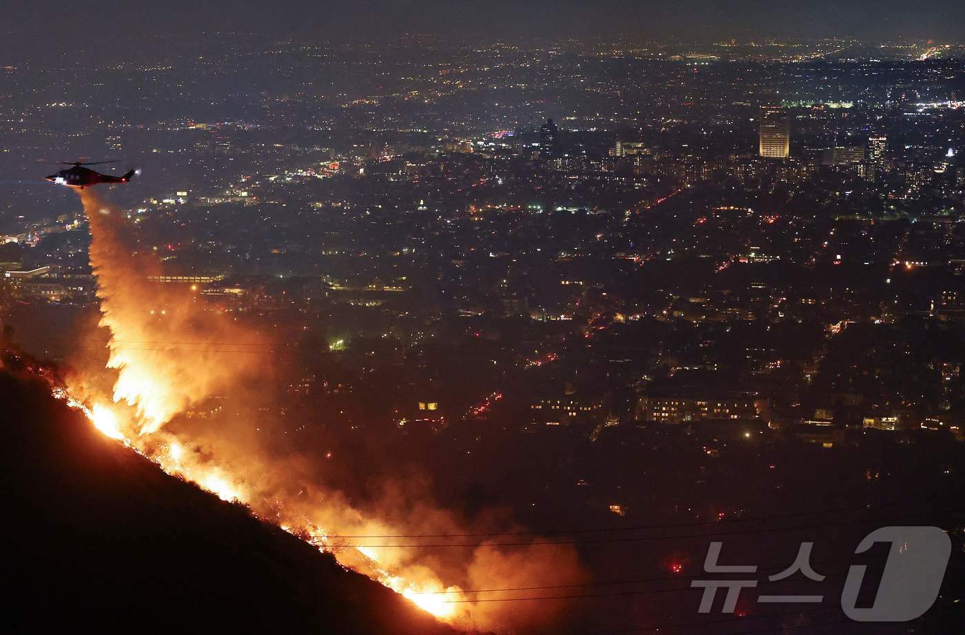 본문 이미지 - 8일&#40;현지시간&#41; 미국 캘리포니아주 로스앤젤레스 할리우드 힐즈에서 발생한 산불에 소방 헬기가 물을 뿌리고 있다. 2025.01.08 ⓒ AFP=뉴스1 ⓒ News1 김지완 기자