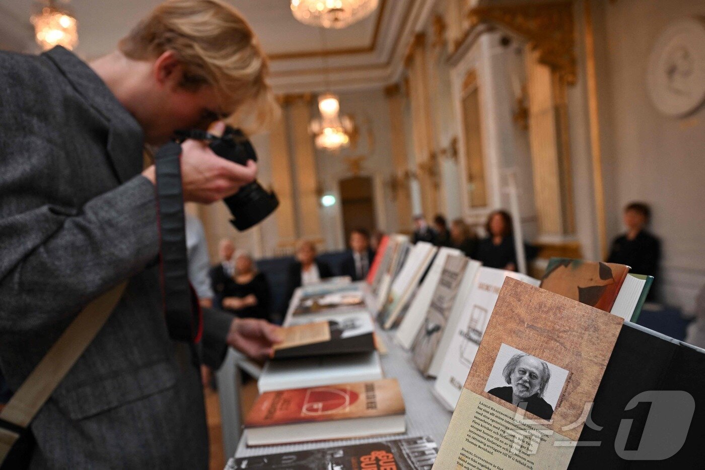 본문 이미지 - 9일&#40;현지시간&#41; 스웨덴 스톡홀름의 스웨덴 아카데미에서 한 사진기자가 2025년 노벨 문학상을 수상한 헝가리 작가 크러스너호르커이 라슬로의 책 사진을 찍고 있다. ⓒ AFP=뉴스1 ⓒ News1 김진환 기자